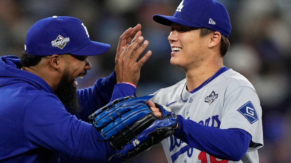 Los Angeles Dodgers pitcher Yoshinobu Yamamoto celebrates with right fielder Teoscar Hernández after throwing compete game against the Toronto Blue Jays in Game 2 of baseball's World Series, Saturday, Oct. 25, 2025, in Toronto.