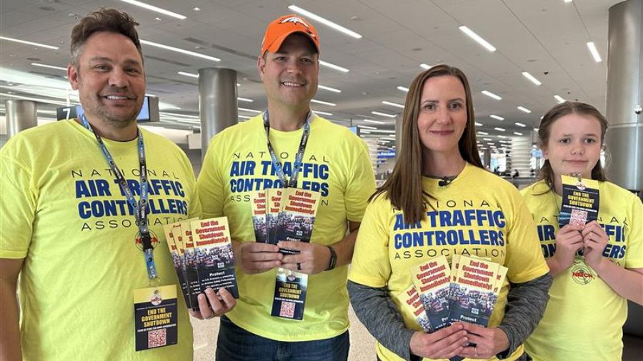 Several air traffic controllers and others gather at the baggage claim area of the Salt Lake City International Airport on their time off, handing out leaflets and urging travelers to pressure lawmakers to end the shutdown so they can get paid, Tuesday, in Salt Lake City.