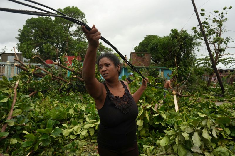 Yurca Melo removes cables from a fallen electrical post on a street in the aftermath of Hurricane Melissa in Santiago, Cuba, Wednesday. The hurricane made landfall early Wednesday in rural Guama.
