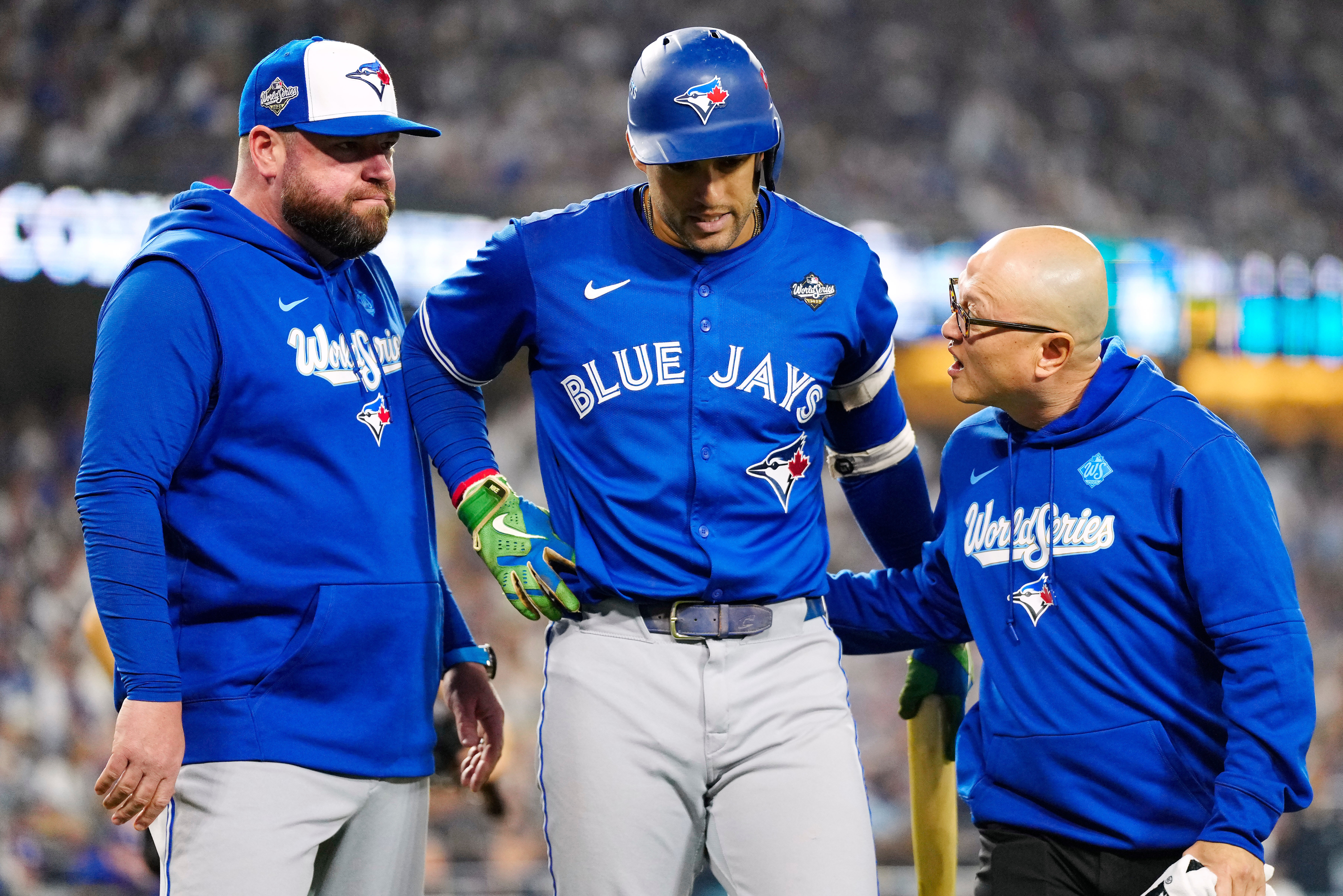 Toronto Blue Jays' George Springer, center, walks off the field as he leaves with an injury with manager John Schneider, left, and first assistant athletic trainer Voon Chong, right, during the seventh inning in Game 3 of baseball's World Series against the Los Angeles Dodgers in Los Angeles, Monday, Oct. 27, 2025.