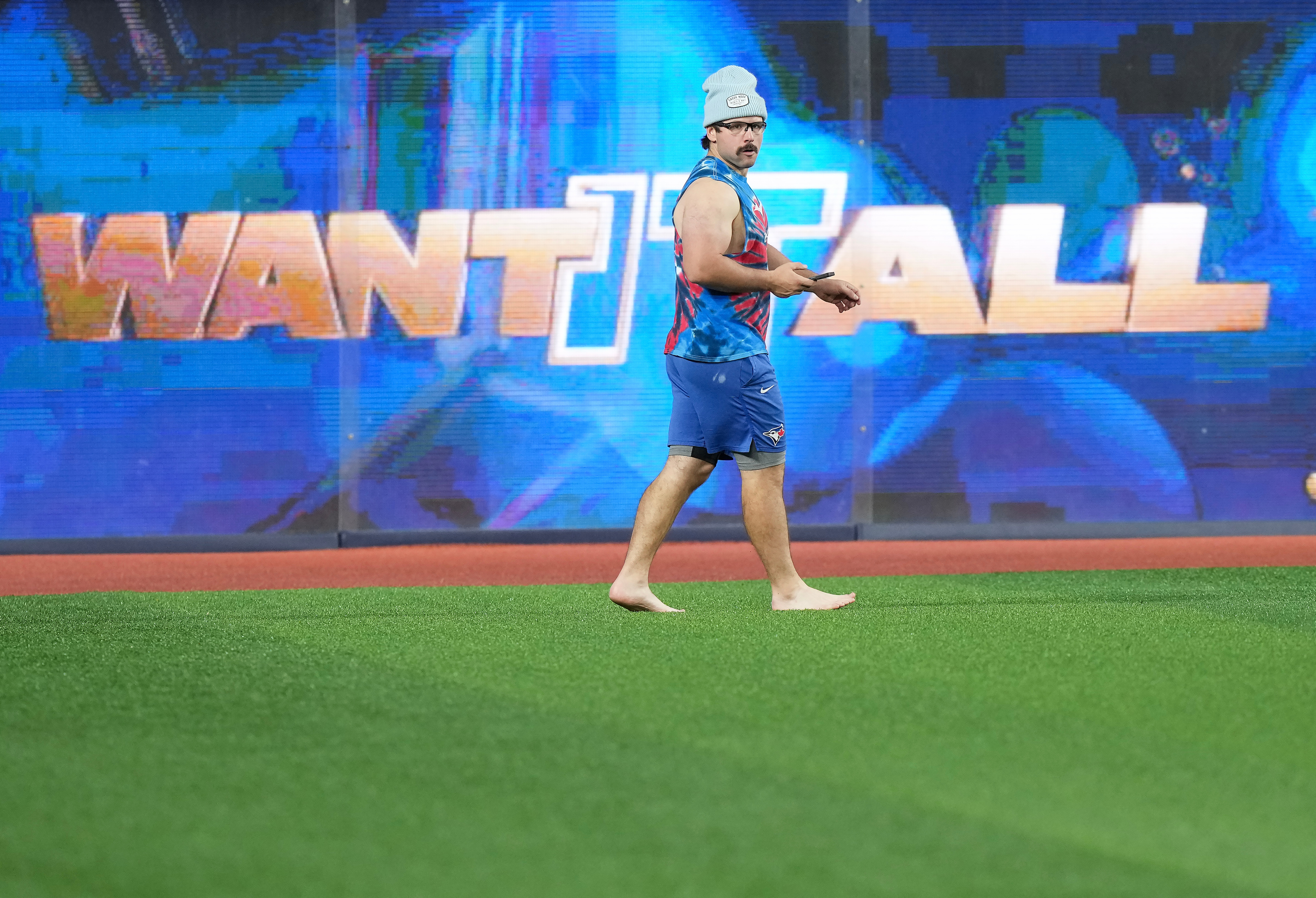 Toronto Blue Jays outfielder Davis Schneider walks barefooted in the outfield during World Series baseball workouts, Thursday, Oct. 30, 2025, in Toronto. 