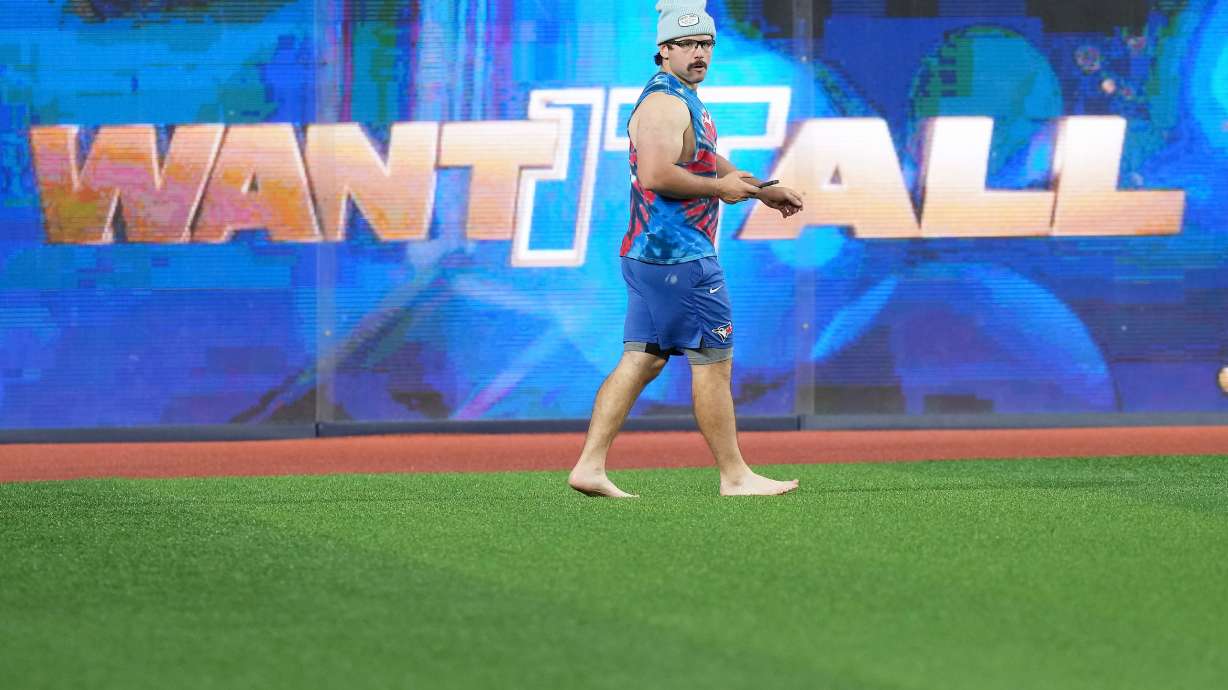 Toronto Blue Jays outfielder Davis Schneider walks barefooted in the outfield during World Series baseball workouts, Thursday, Oct. 30, 2025, in Toronto.