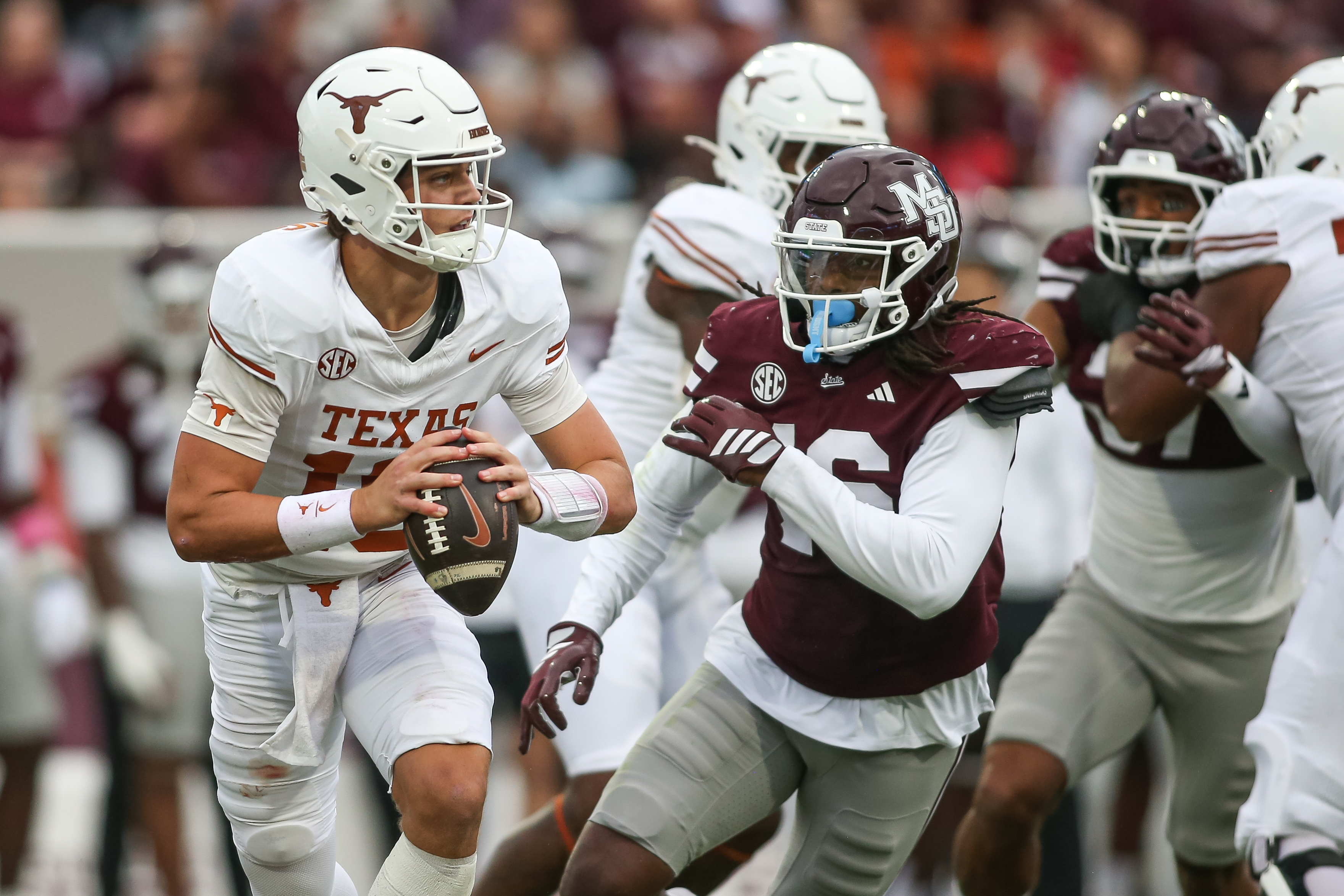 Texas quarterback Arch Manning, left, scrambles out of the pocket against Mississippi State linebacker Derion Gullette, front right, during the first half of an NCAA college football game in Starkville, Miss., Saturday, Oct. 25, 2025. 
