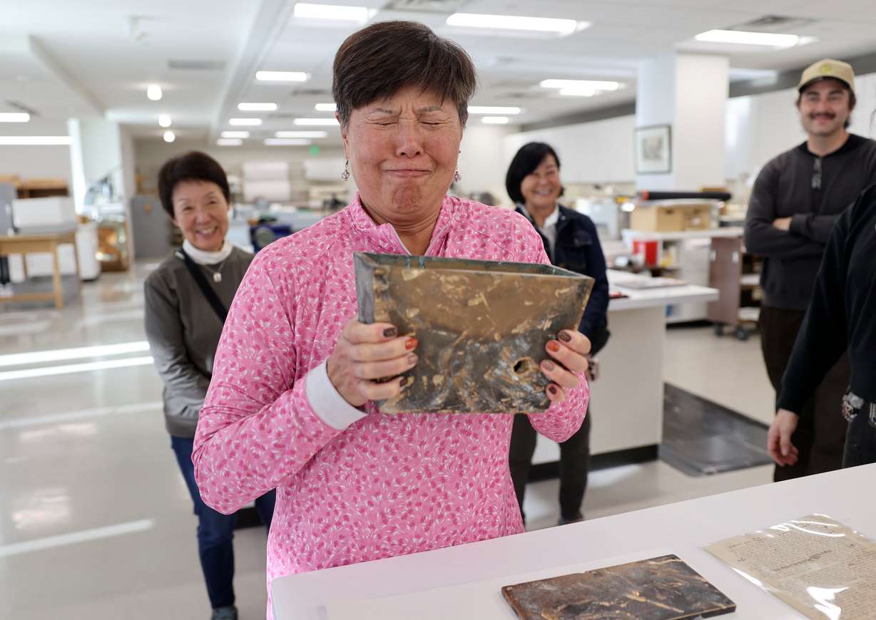 Tammy Nakamura, Japanese Church of Christ member and time capsule committee member, reacts as she holds a heavy container used for the Japanese Church of Christ’s 101-year-old time capsule at the University of Utah Marriott Library Preservation Department in Salt Lake City on Oct. 20.