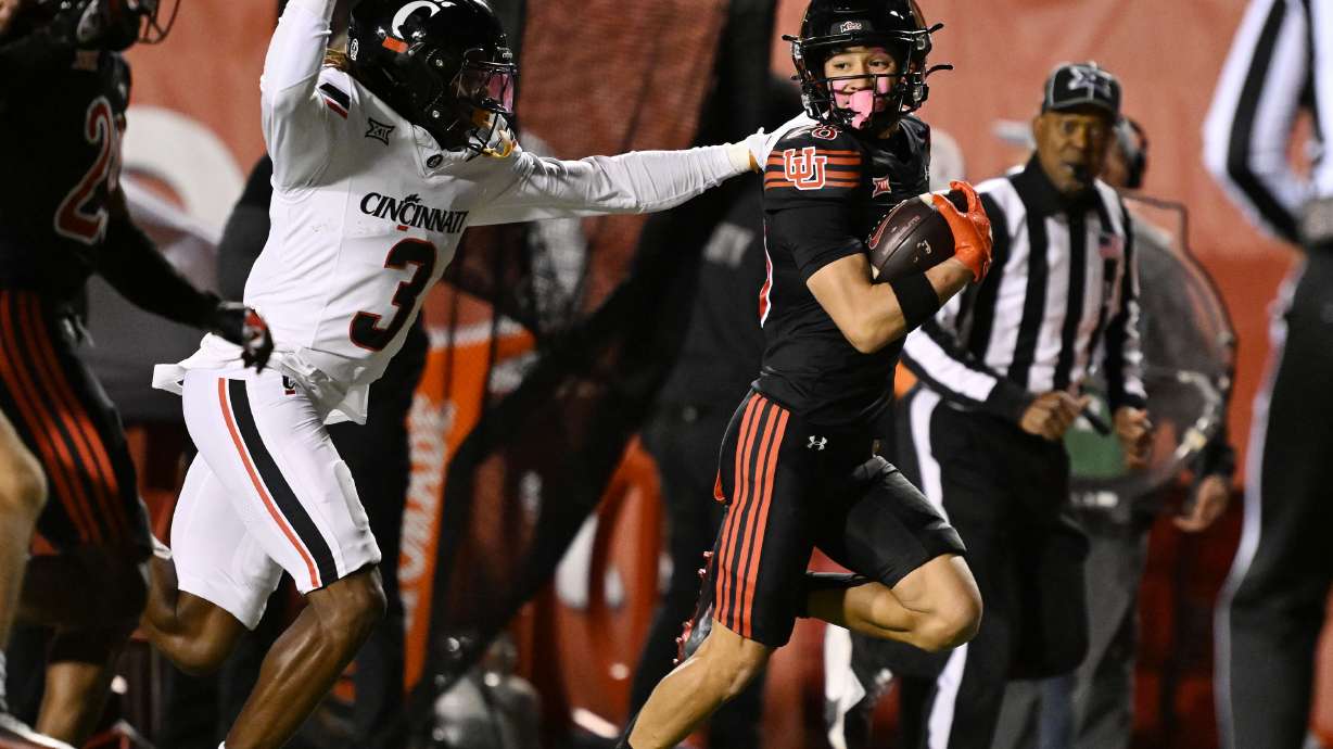 Cincinnati Bearcats defensive back Kye Stokes (3) attempts to knock the ball away from Utah Utes wide receiver Mana Carvalho (28) as he looks to his right during a punt return for a touchdown as Utah and Cincinnati play at Rice Eccles Stadium in Salt Lake City on Saturday, Nov. 1, 2025.
