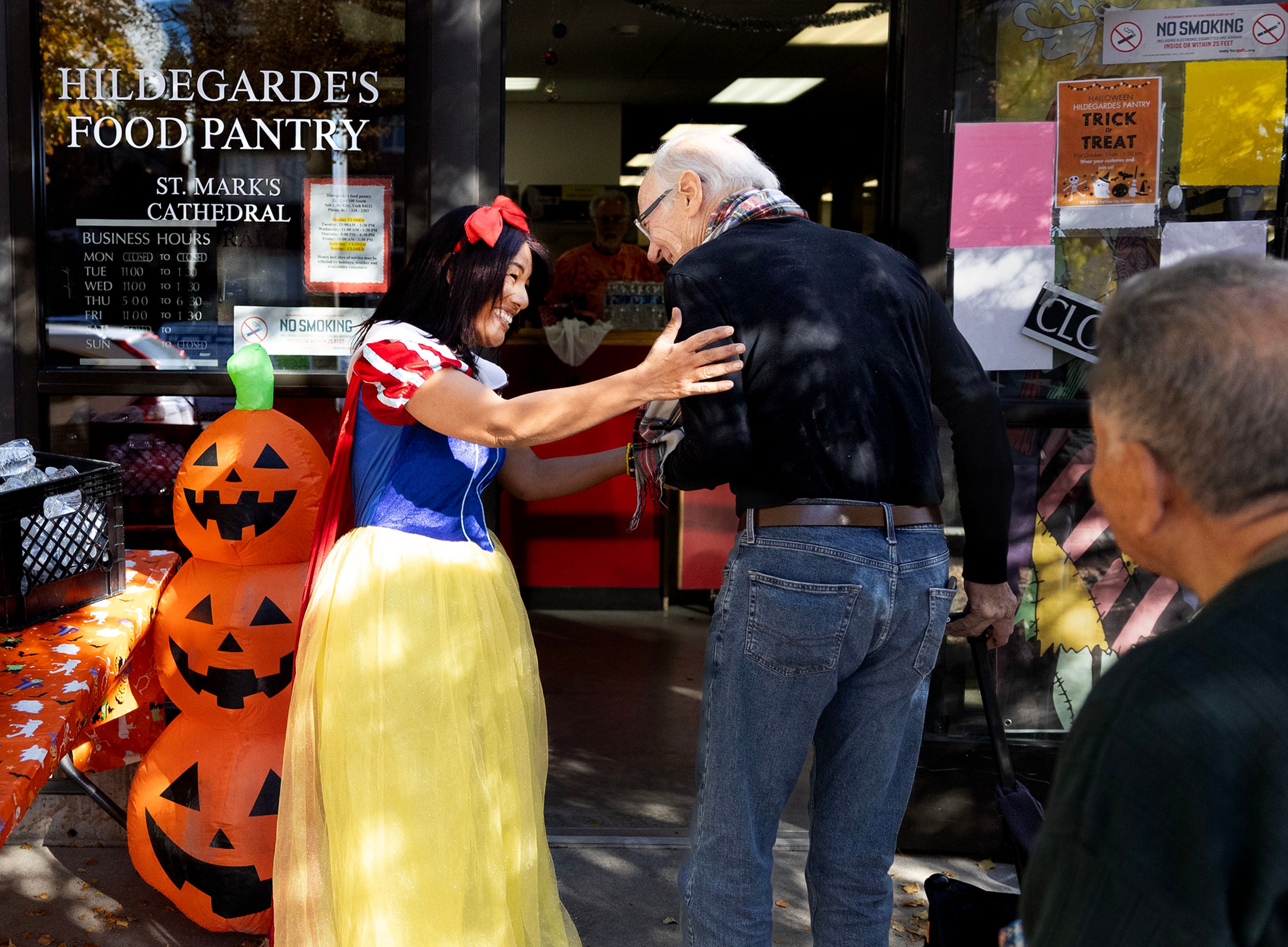 Hildegarde's Food Pantry manager Cibell Morales-Brown, dressed as Snow White for Halloween, greets John McCarthy as the pantry opens in Salt Lake City on Friday.