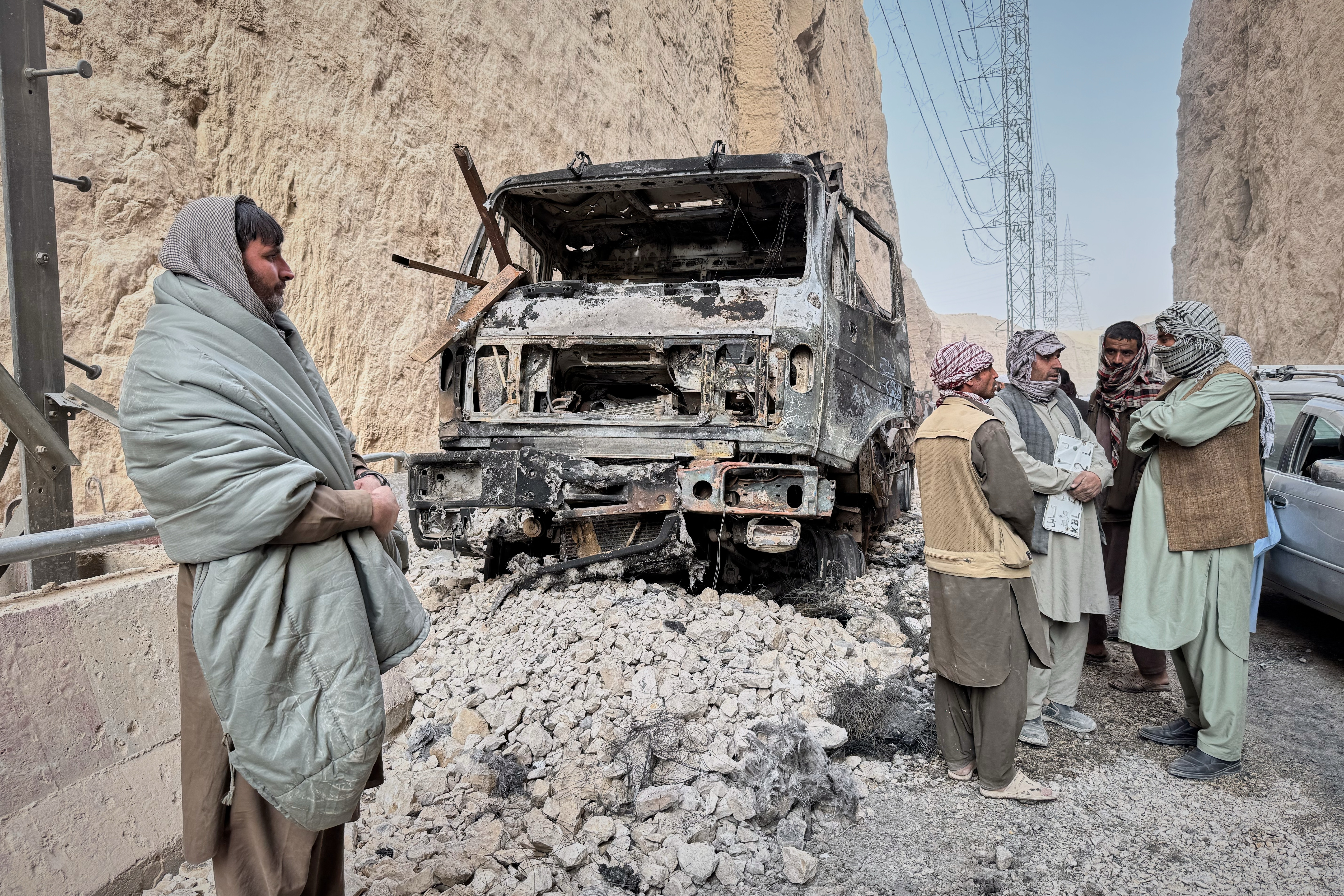 Local officials confer next to a burned-out truck that caught fire from power cables as they try to reach affected areas during a powerful 6.3-magnitude earthquake in a rural part of the Khulm District in Samangan Province, northern Afghanistan, on Monday.