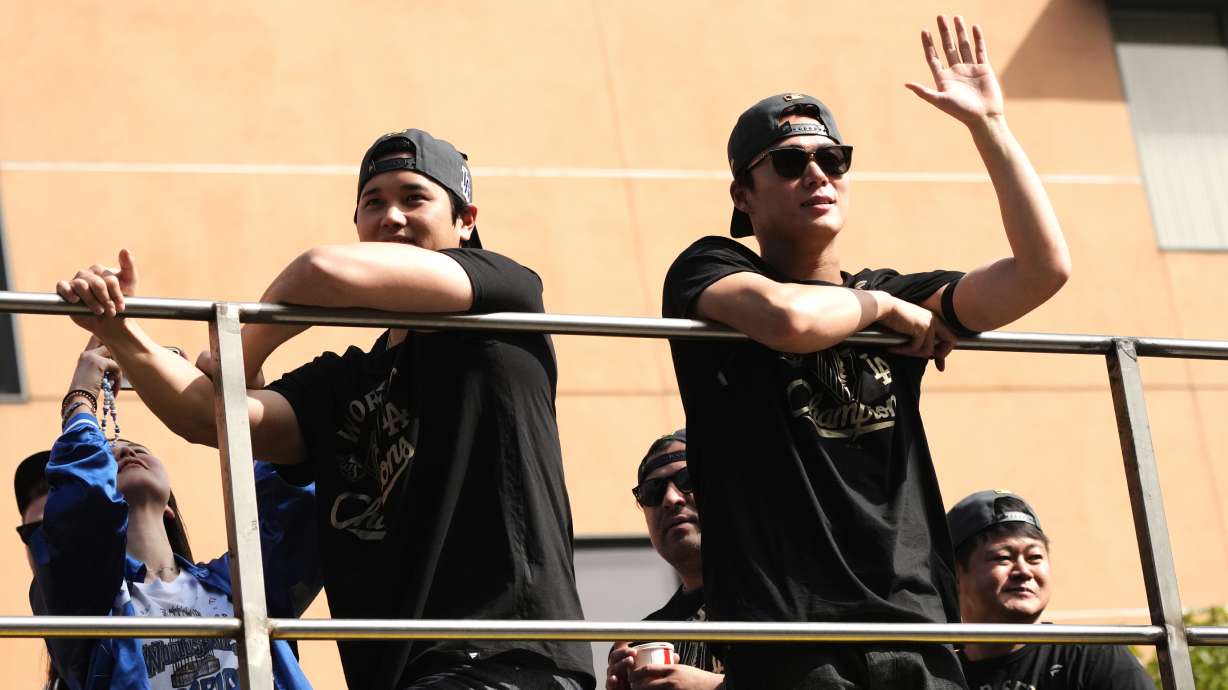 Los Angels Dodgers' Shohei Ohtani, left, and Yoshinobu Yamamoto wave from a double-decker bus during a parade to celebrate the baseball team's World Series win on Monday, Nov. 3, 2025, in Los Angeles.