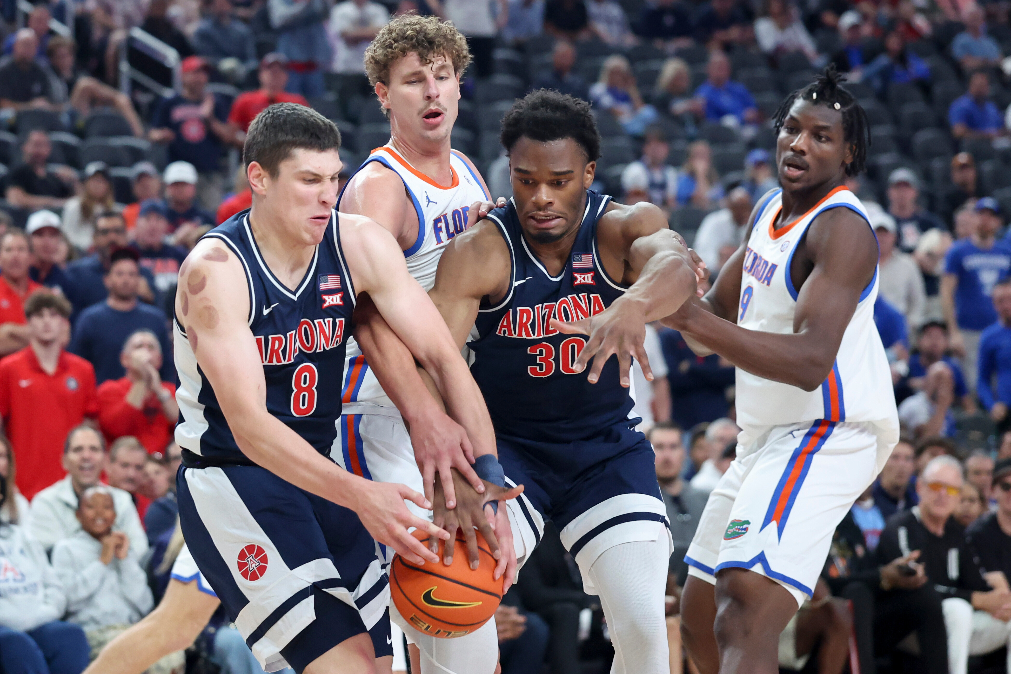 Arizona forwards Ivan Kharchenkov (8) and Tobe Awaka (30) contest for a rebound against Florida center Micah Handlogten, second from left, during the first half of an NCAA college basketball game, Monday, Nov. 3, 2025, in Las Vegas.