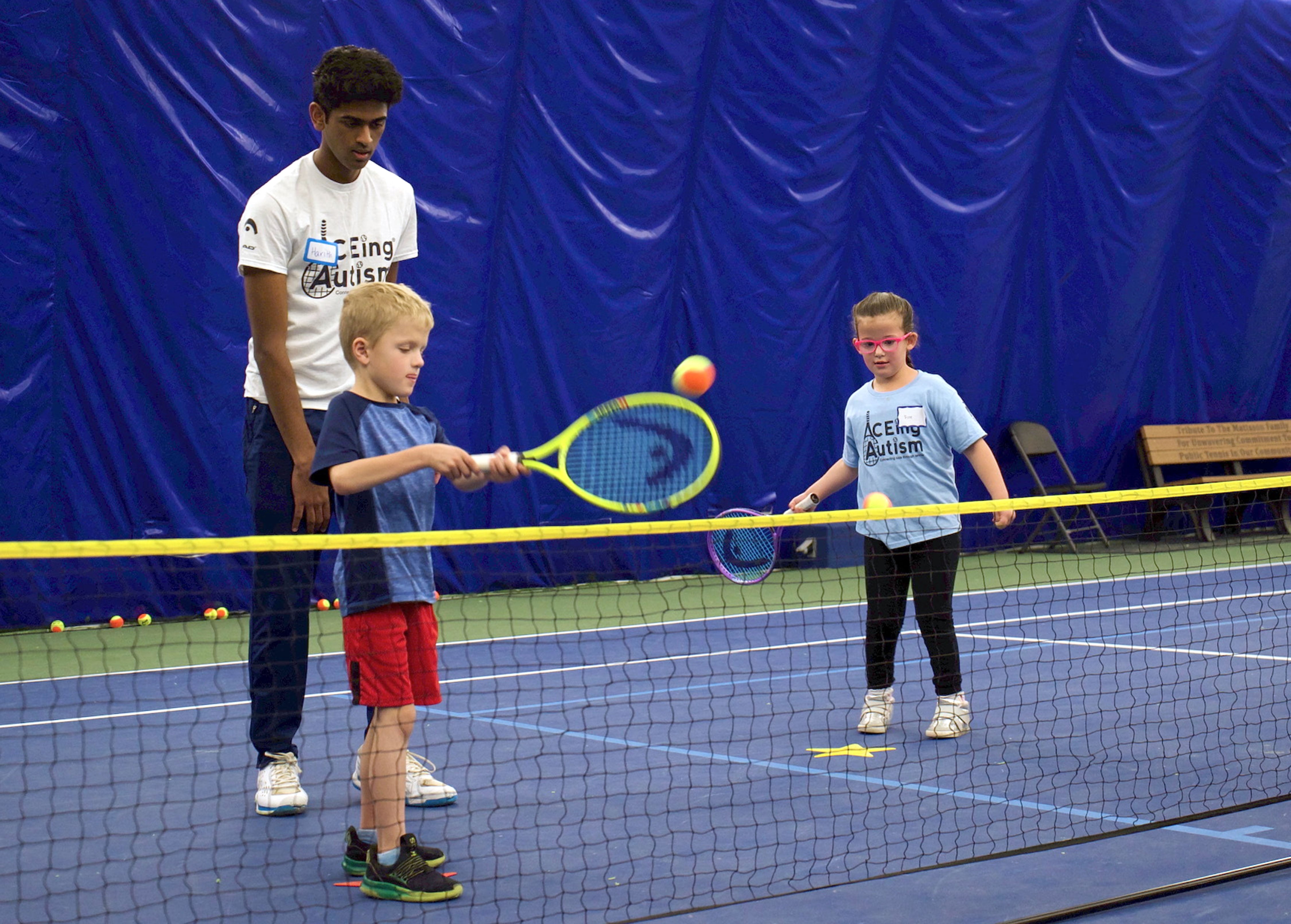Jack Marshall, 7, swings a racket with a volunteer with ACEing Autism's fall 2025 tennis clinic.