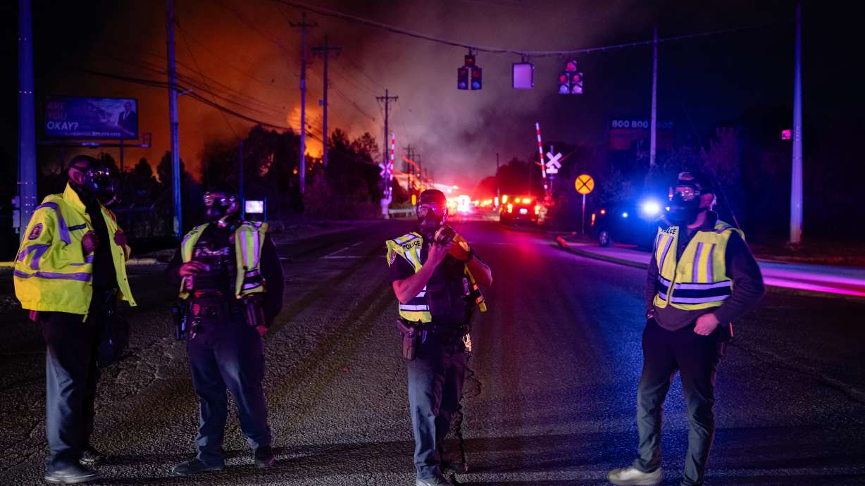 Members of law enforcement wear respirators near the area of the reported plane crash at Louisville Muhammad Ali International Airport on Tuesday, in Louisville, Ky. At least seven people are dead and 11 more are injured from the crash.