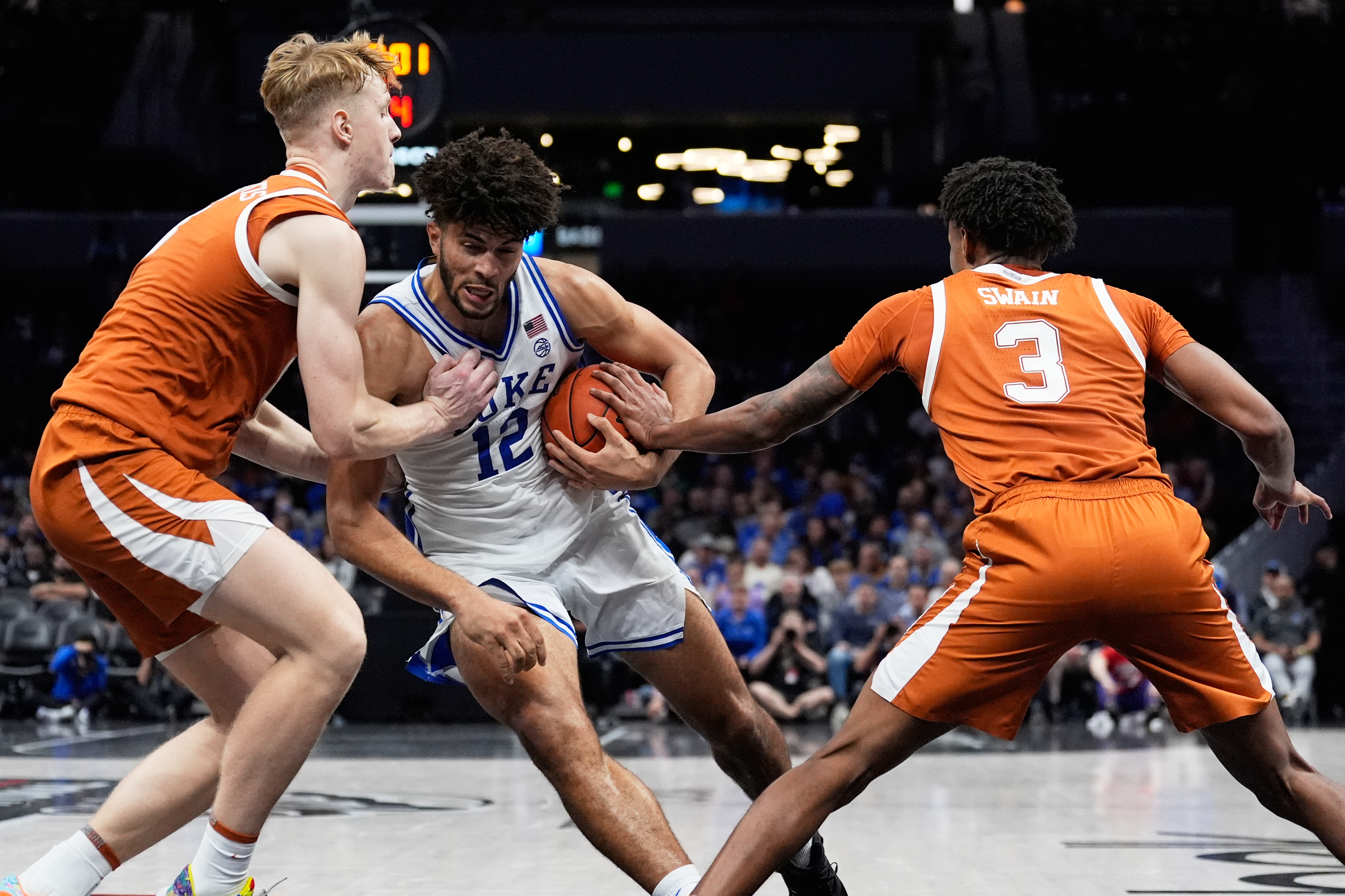Duke forward Cameron Boozer drives to the basket between Texas center Matas Vokietaitis, left, and forward Dailyn Swain during the second half of an NCAA college basketball game, Tuesday, Nov. 4, 2025, in Charlotte, N.C.