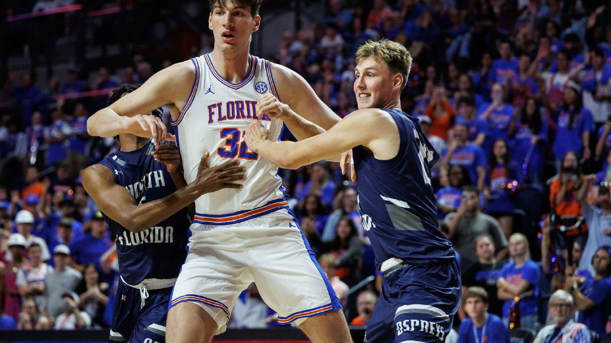 CORRECTS TO SECOND HALF NOT FIRST HALF - North Florida guard Dante Oliver, left and North Florida forward Nestor Dyachok, right, guard against Florida center Olivier Rioux, center, during the second half of an NCAA college basketball game Thursday, Nov. 6, 2025, in Gainesville, Fla.