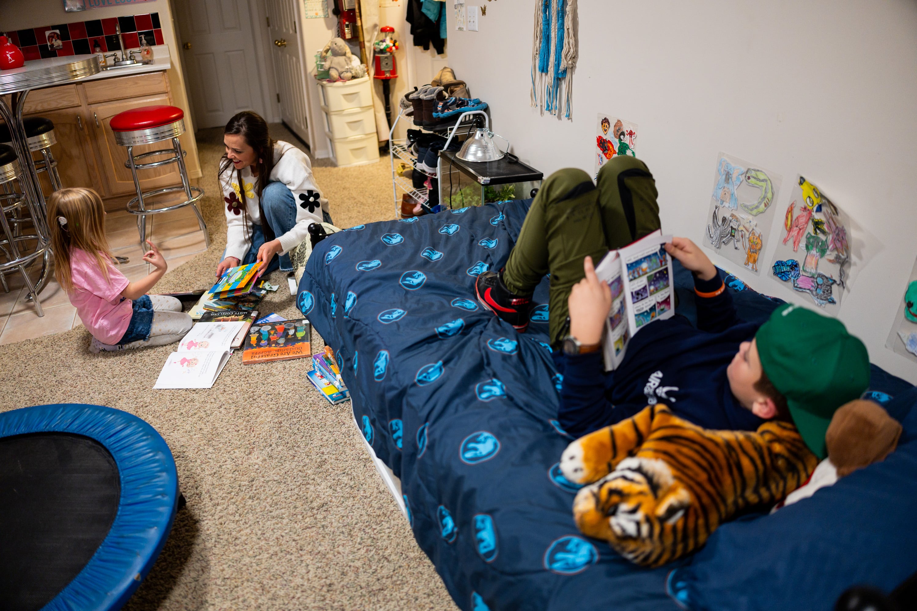 Philly Clancy, 5, a student at the Jean Massieu School of the Deaf, picks out a book to read with her mother Stephanie Clancy, movement teacher at Majestic Elementary Arts Academy, left, while brother Boston Clancy, 8, right, reads a book on his bed at their home in South Jordan on Thursday. Brian Clancy said a parent's relationship with their educator is crucial to their success.