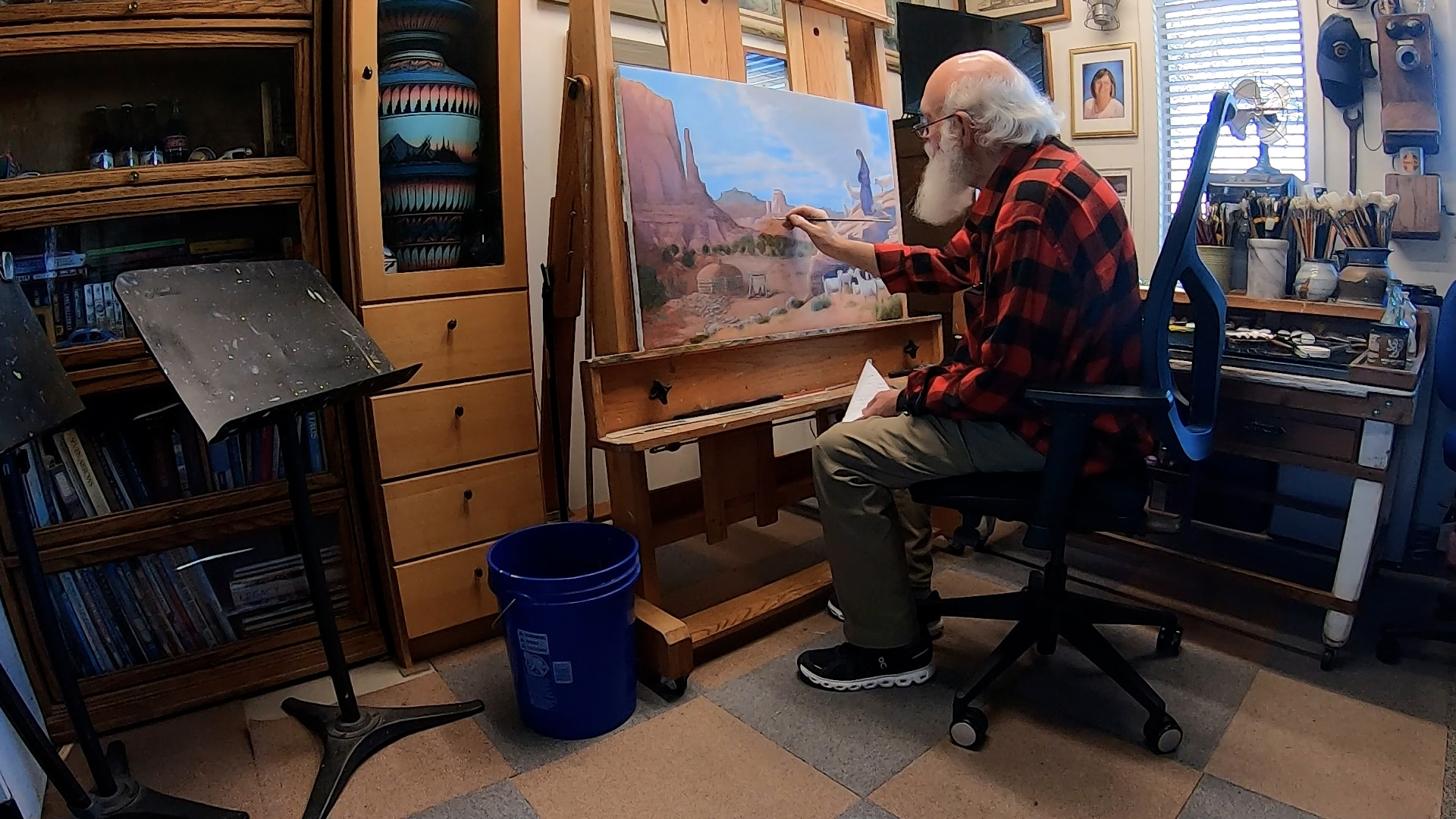 Arlo Johnson paints a red rock landscape, Monday. Johnson said he finds peace in painting the surroundings of where he grew up.