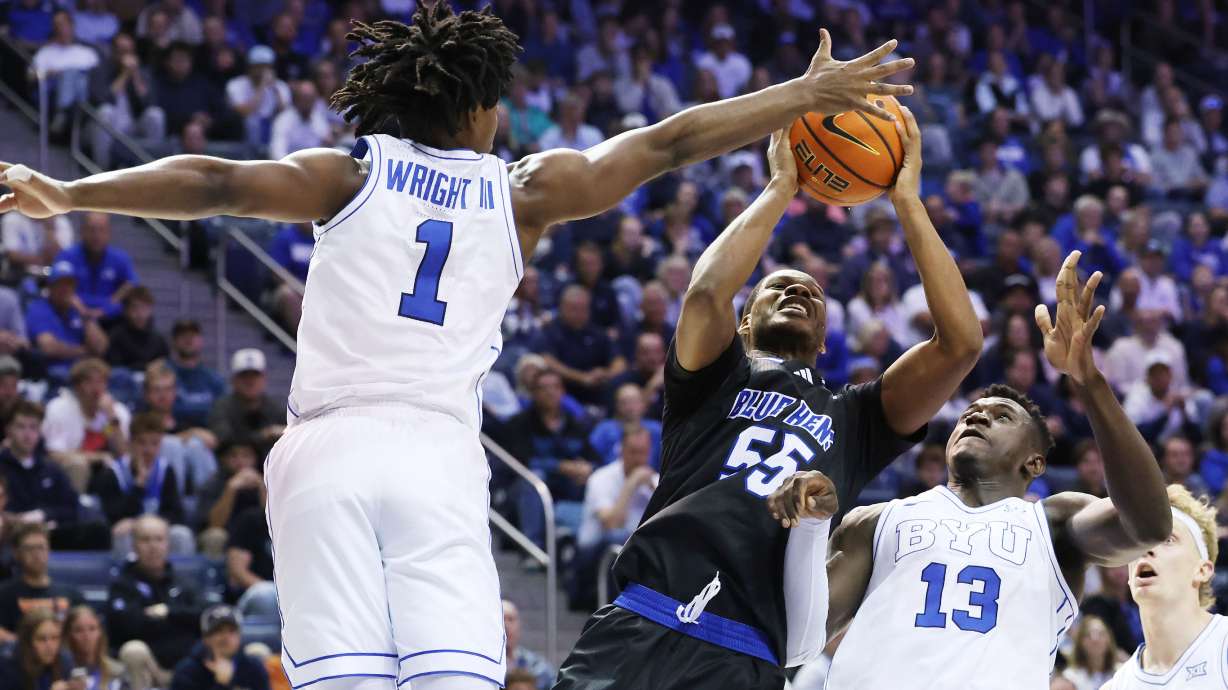 Delaware guard Jameel Brown tries top shoot on BYU guard Robert Wright III during the first half of an NCAA college basketball game Tuesday, Nov. 11, 2025, in Provo, Utah.