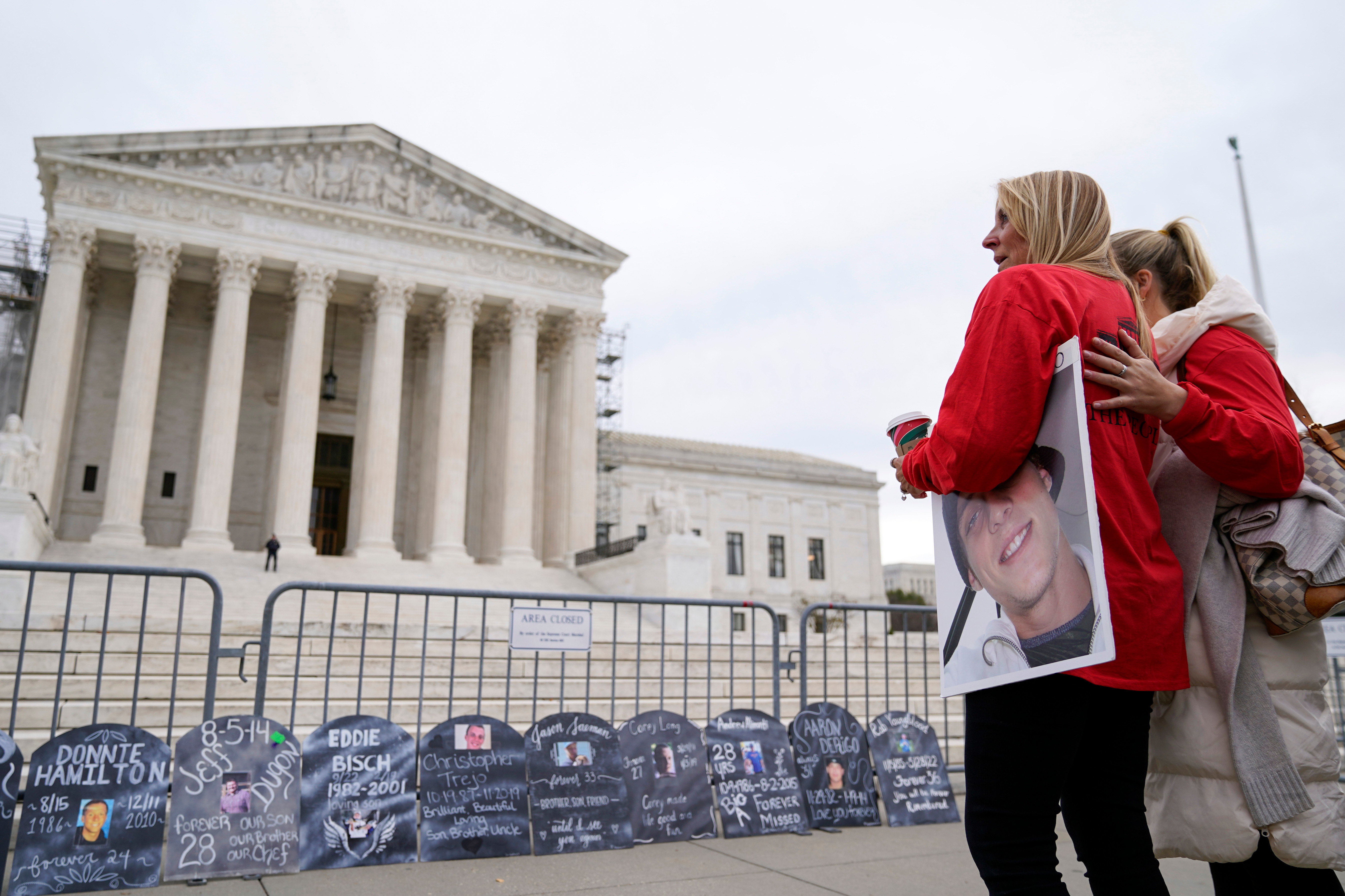 Jen Trejo holds a photo of her son Christopher as she is comforted outside the Supreme Court Dec. 4, 2023, in Washington. A federal bankruptcy court judge on Friday said he will approve OxyContin-maker Purdue Pharma's latest deal to settle thousands of lawsuits.