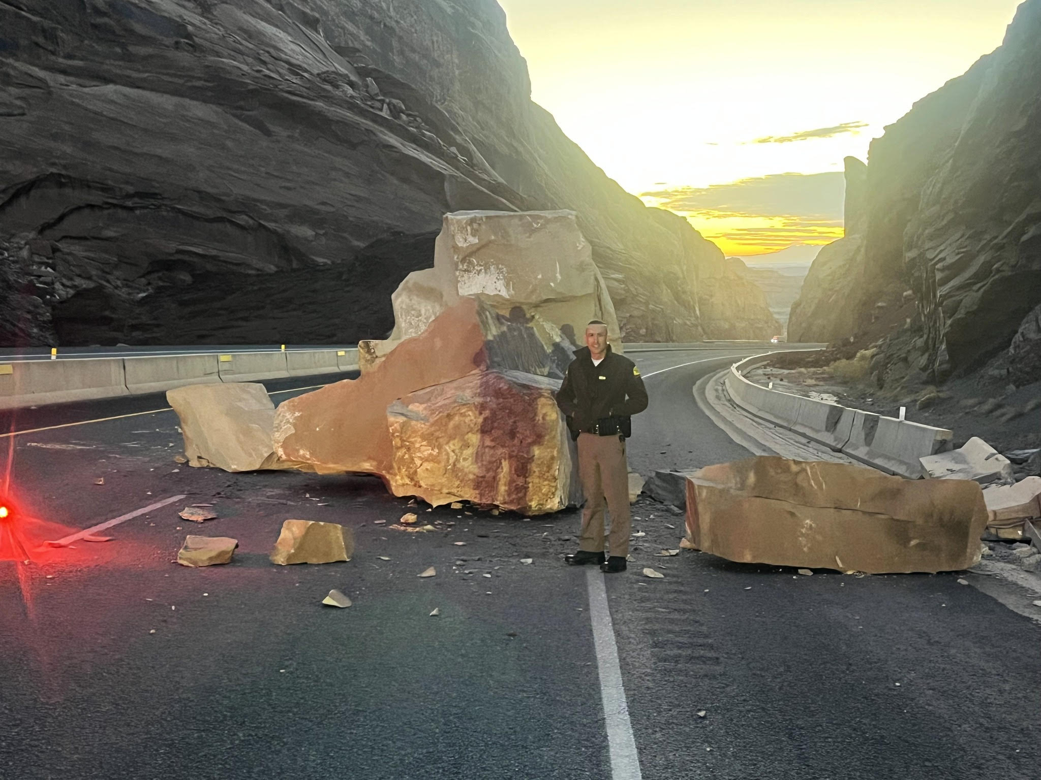 Utah Highway Patrol Trooper Dakota Adams is seen standing next to a rock that fell onto Interstate 70 near Green River early Thursday morning.