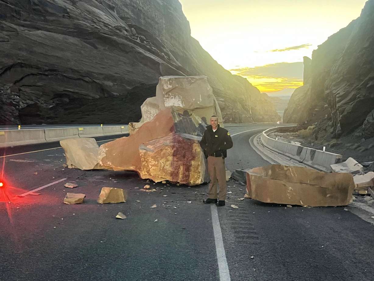 Utah Highway Patrol Trooper Dakota Adams is seen standing next to a rock that fell onto Interstate 70 near Green River early Thursday morning.