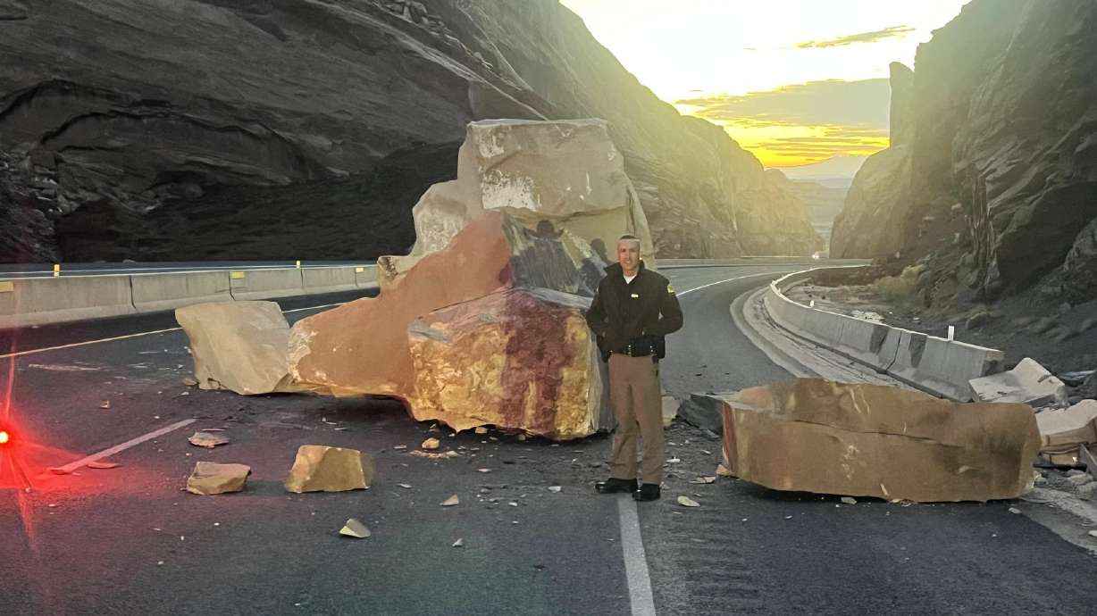 Utah Highway Patrol trooper Dakota Adams is seen standing next to a rock that fell onto I-70 near Green River early Thursday.
