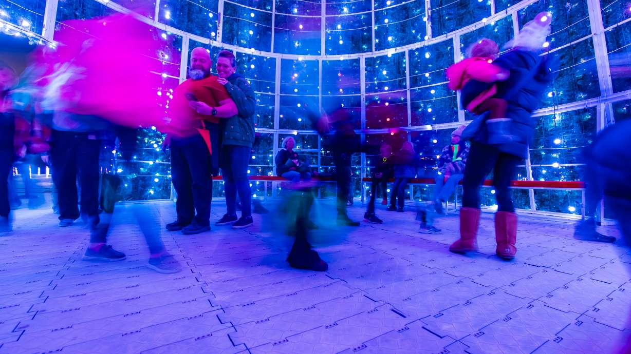 People walk underneath a 60-foot replica Christmas tree as part of Holiday Lights at the Ballpark at America First Square in South Jordan on Friday.