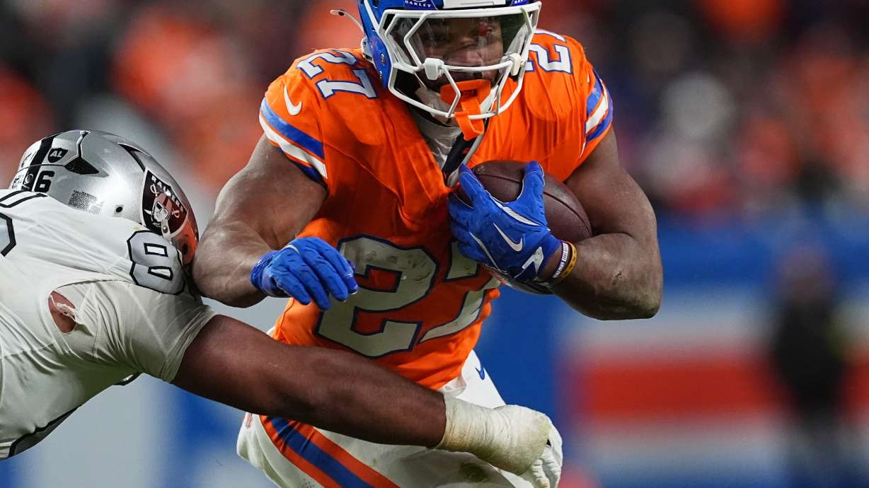 Denver Broncos running back J.K. Dobbins, right, runs for a first-down as Las Vegas Raiders defensive tackle Jonah Laulu makes the stop in the second half of after an NFL football game Thursday, Nov. 6, 2025, in Denver.