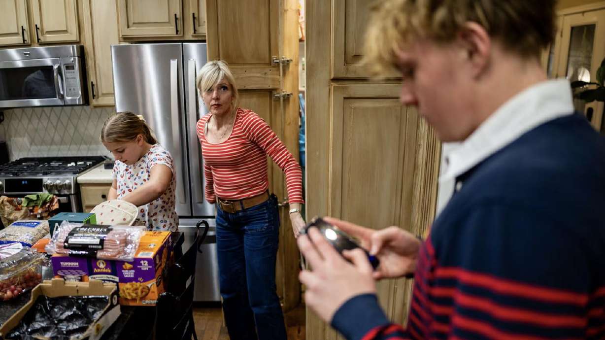 Jennifer Long, center, walks out of the pantry to see son Henry Long, 16, on his phone while daughter Emily Long, 10, left, helps unload groceries at their home in Bountiful on Nov. 6.
