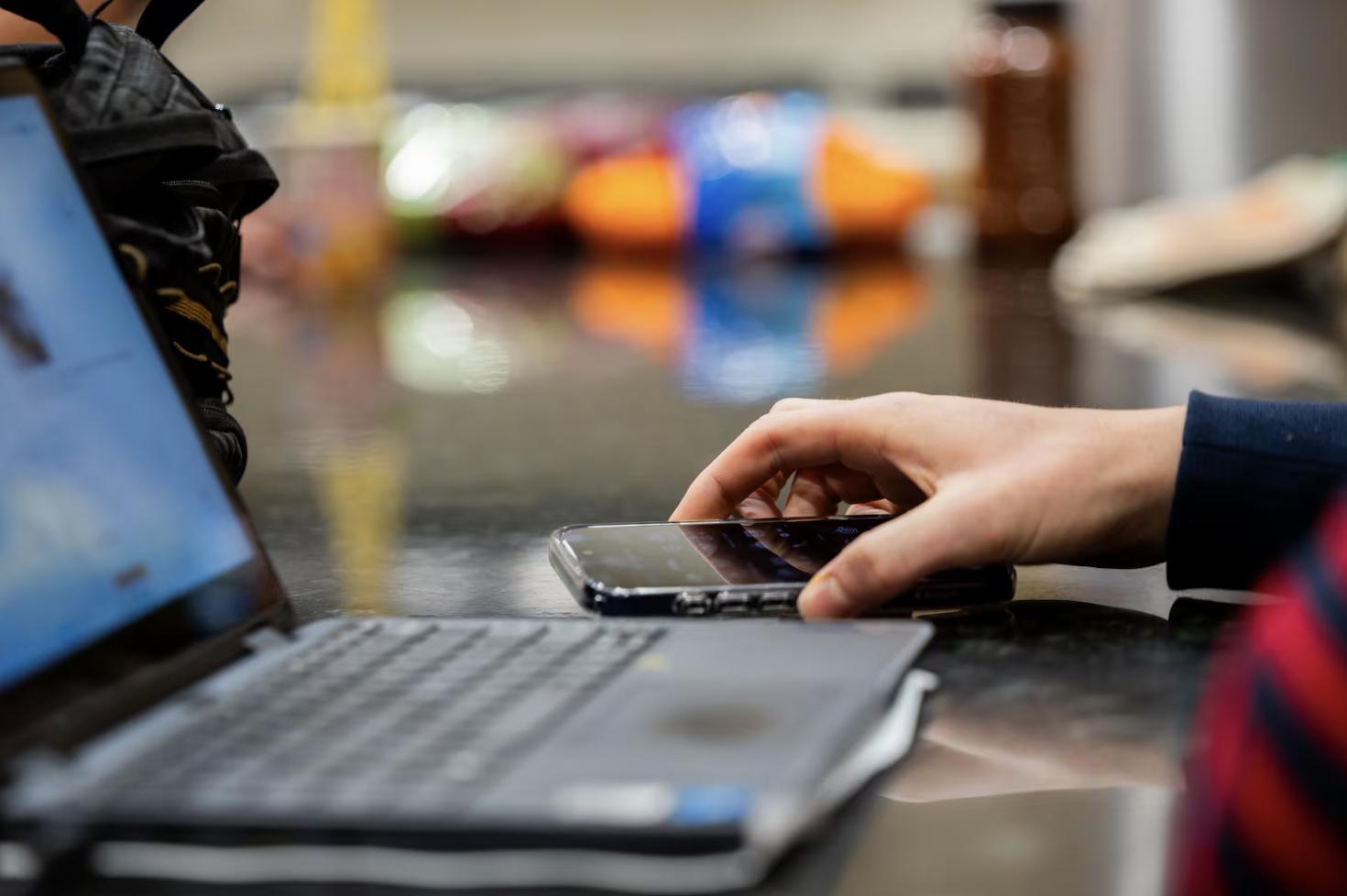 Henry Long, 16, reaches for his phone while doing homework at his home in Bountiful on Nov. 6.