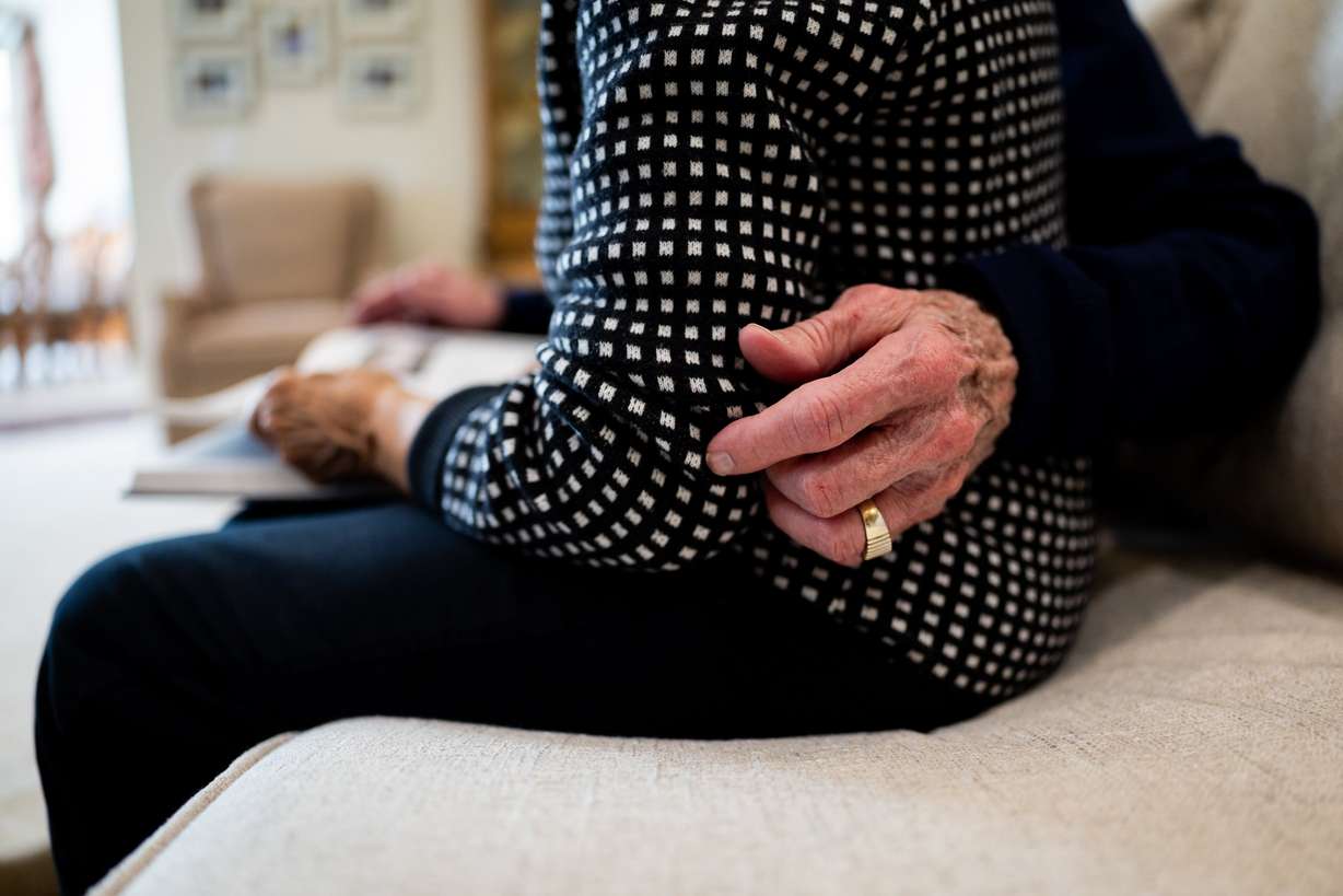 Kelvyn Cullimore wraps his arm around wife Kay Cullimore as the pair poses while looking at their personal history book they made in 2021 at their home in Cottonwood Heights on Nov. 5.