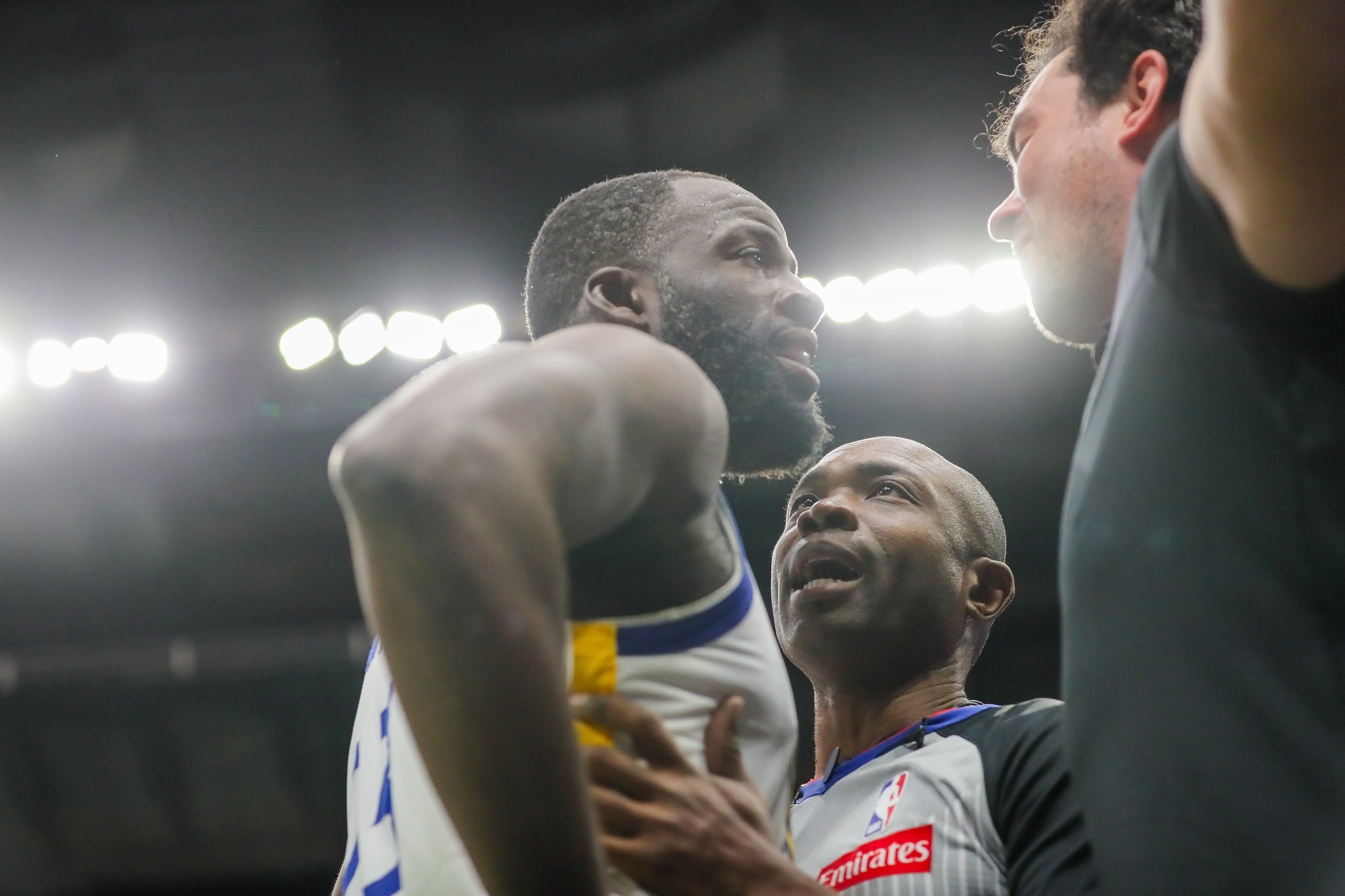Golden State Warriors forward Draymond Green (23) is held back by referee Courtney Kirkland while talking to New Orleans Pelicans fan Sam Green during the first half of an NBA basketball game against the New Orleans Pelicans in New Orleans, Sunday, Nov. 16, 2025.