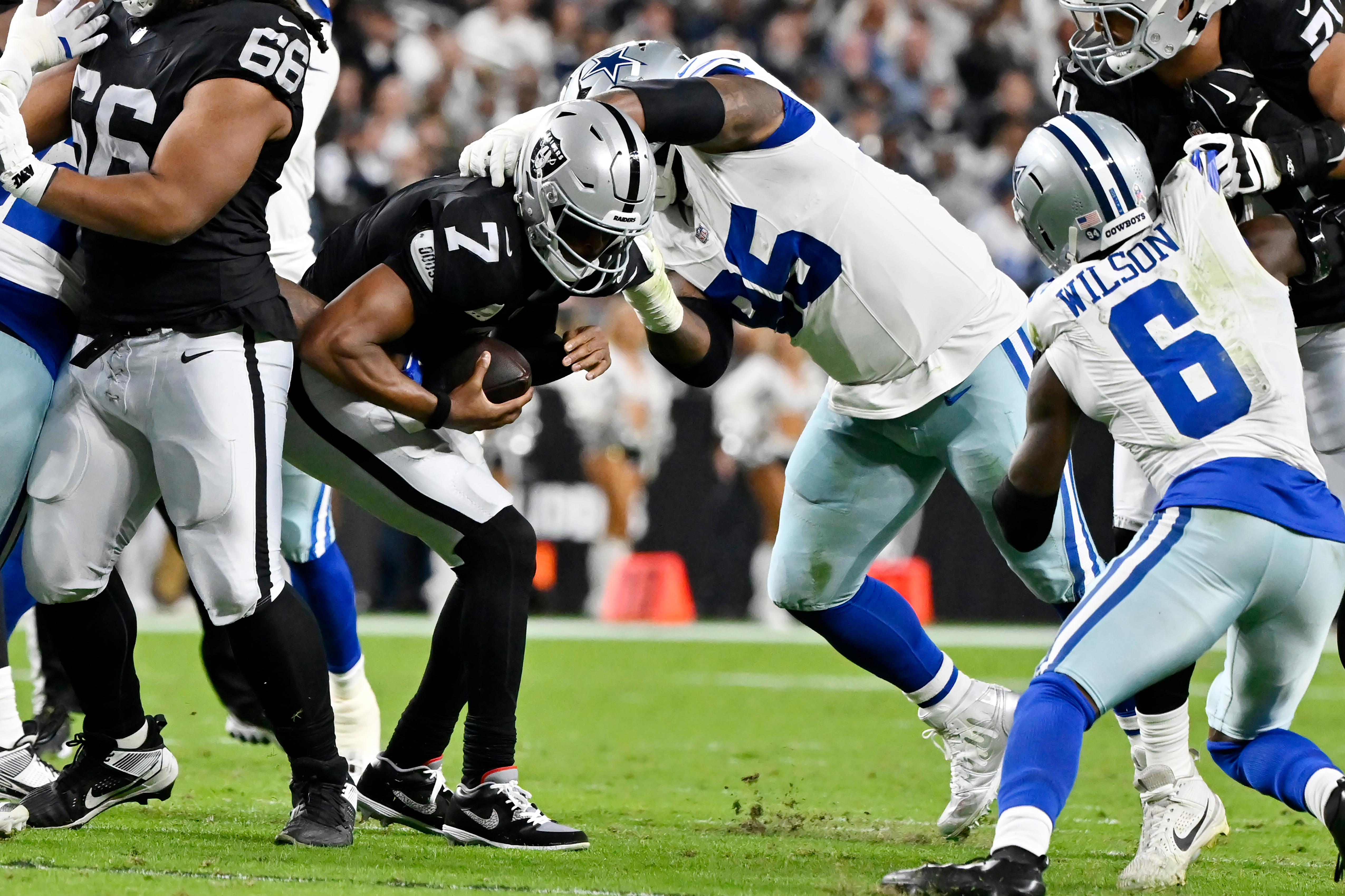 Dallas Cowboys defensive tackle Kenny Clark, second from right, sacks Las Vegas Raiders quarterback Geno Smith (7) as Cowboys safety Donovan Wilson (6) looks on during the first half of an NFL football game Monday, Nov. 17, 2025, in Las Vegas.