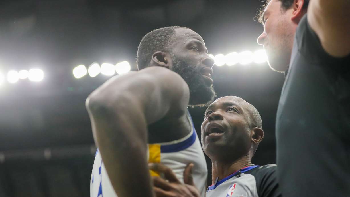 Golden State Warriors forward Draymond Green (23) is held back by referee Courtney Kirkland while talking to New Orleans Pelicans fan Sam Green during the first half of an NBA basketball game against the New Orleans Pelicans in New Orleans, Sunday, Nov. 16, 2025.