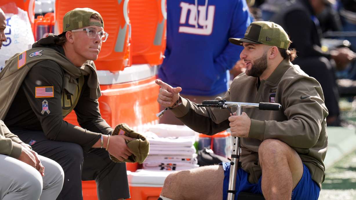 New York Giants' injured players Cam Skattebo and Jaxson Dart talk before an NFL football game against the Green Bay Packers Sunday, Nov. 16, 2025, in East Rutherford, N.J.