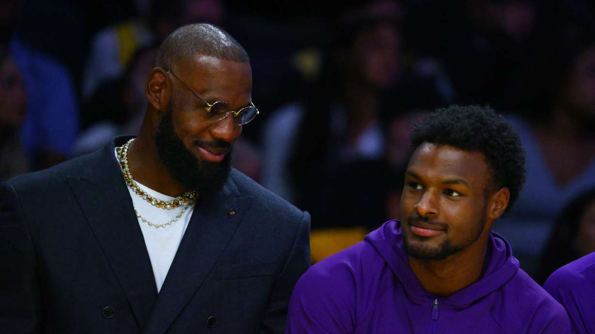 Los Angeles Lakers forward Lebron James, left, talks to guard Bronny James during the first half of an NBA basketball game against the Golden State Warriors, Tuesday, Oct. 21, 2025, in Los Angeles.