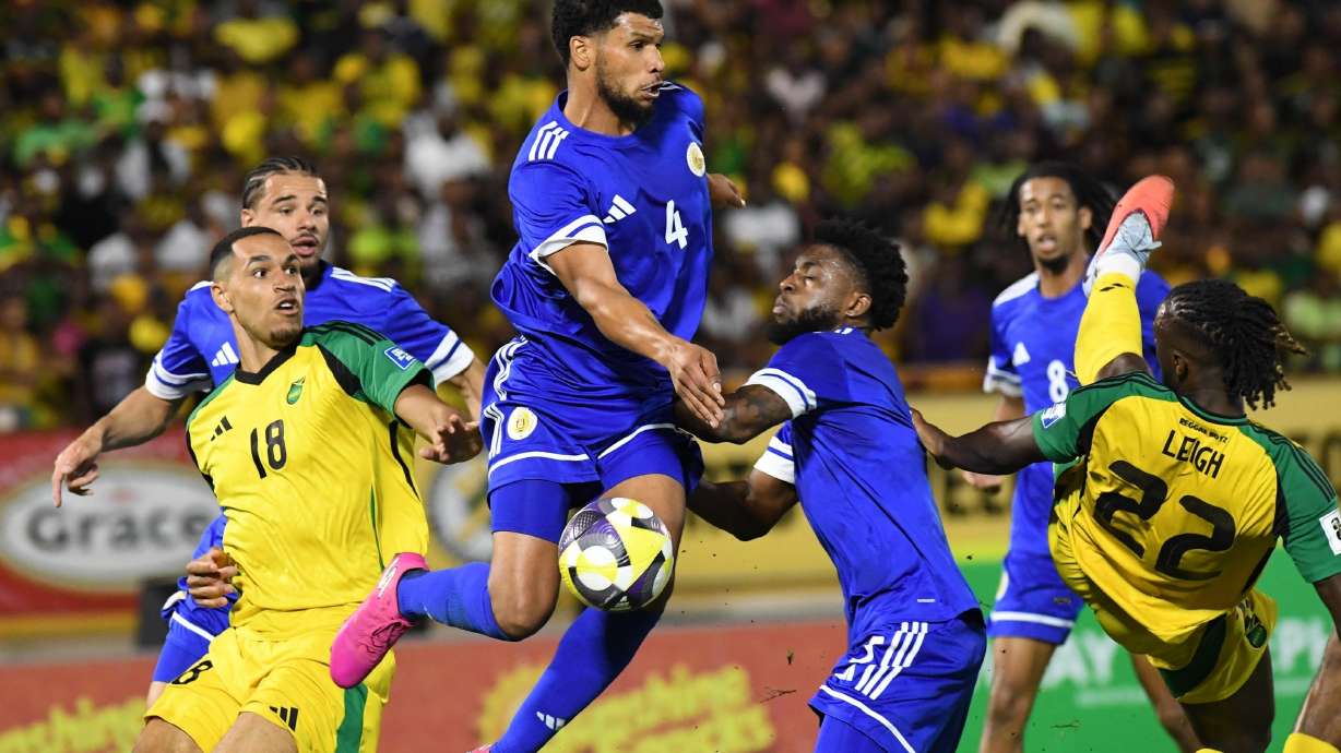 Curacao's Roshon Van Eijma, in the air, fights for the ball with Jamaica's Gregory Leigh, right, and Jonathan Russell during a World Cup 2026 qualifying soccer match in Kingston, Jamaica, Tuesday, Nov. 18, 2025.