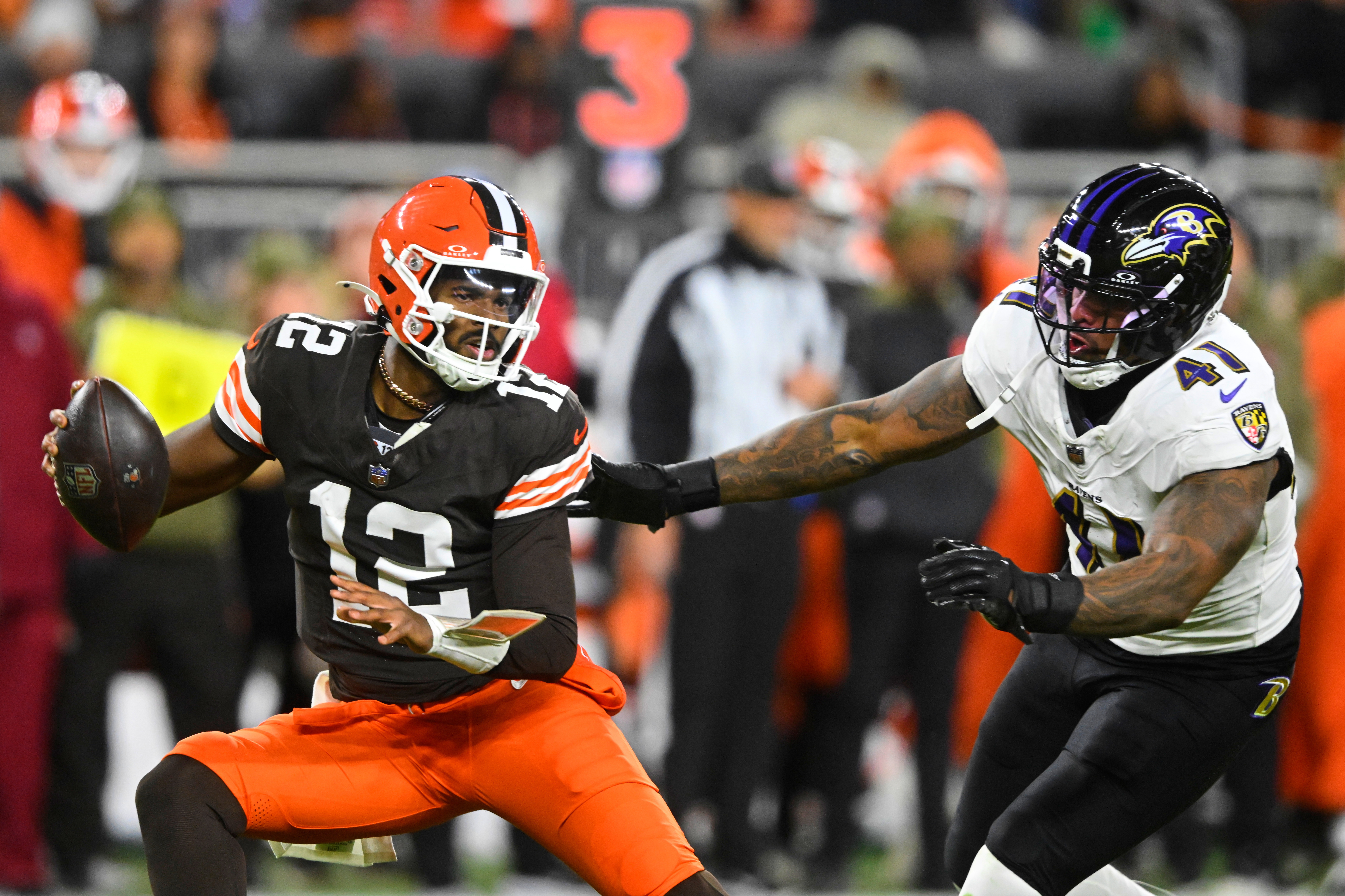 Cleveland Browns quarterback Shedeur Sanders (12) is pressured out of the pocket by Baltimore Ravens' Dre'Mont Jones (41) in the second half of an NFL football game in Cleveland, Sunday, Nov. 16, 2025.