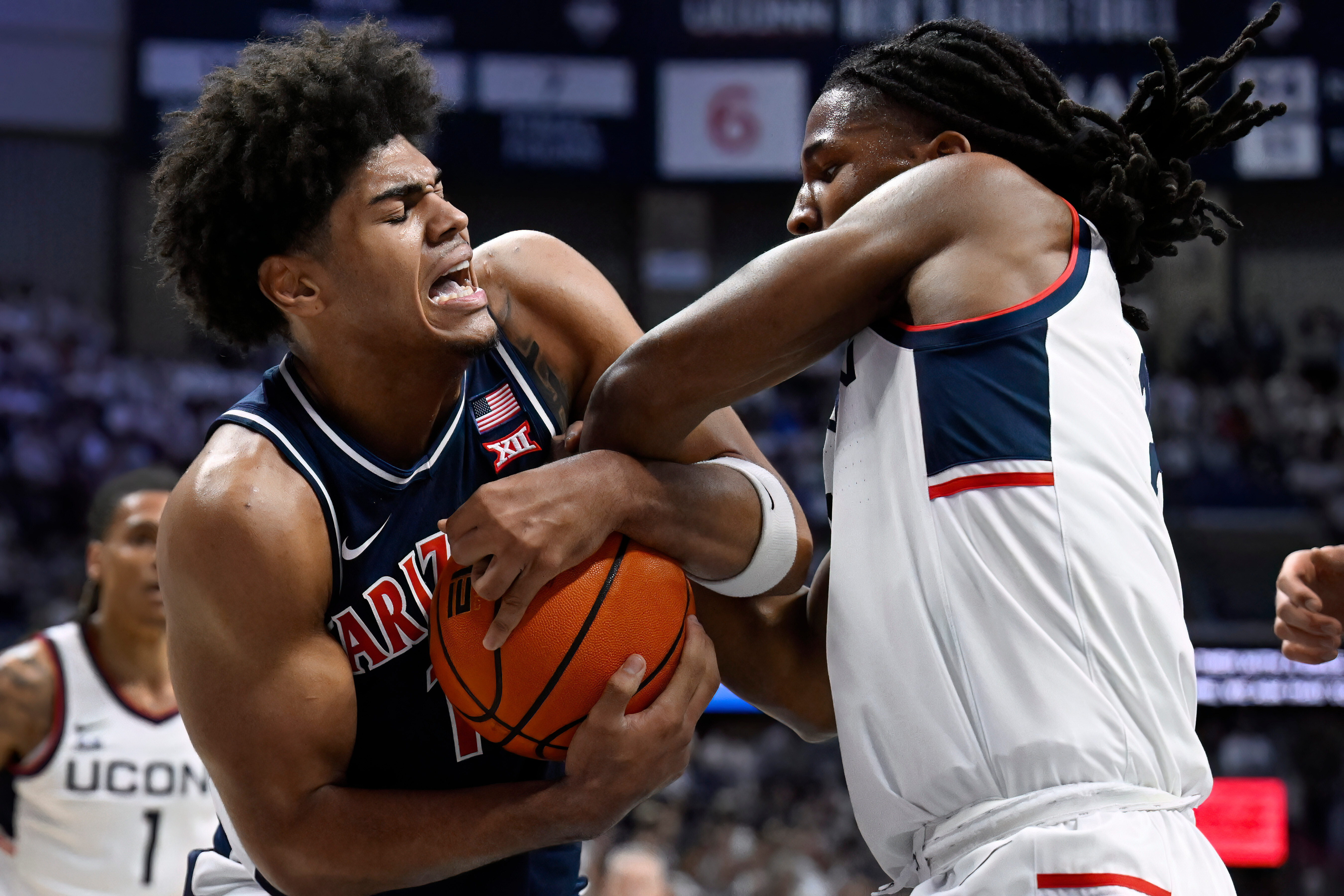 Arizona forward Koa Peat and UConn guard Silas Demary Jr., right, fight for possession of the ball in the first half of an NCAA college basketball game, Wednesday, Nov. 19, 2025, in Storrs, Conn.