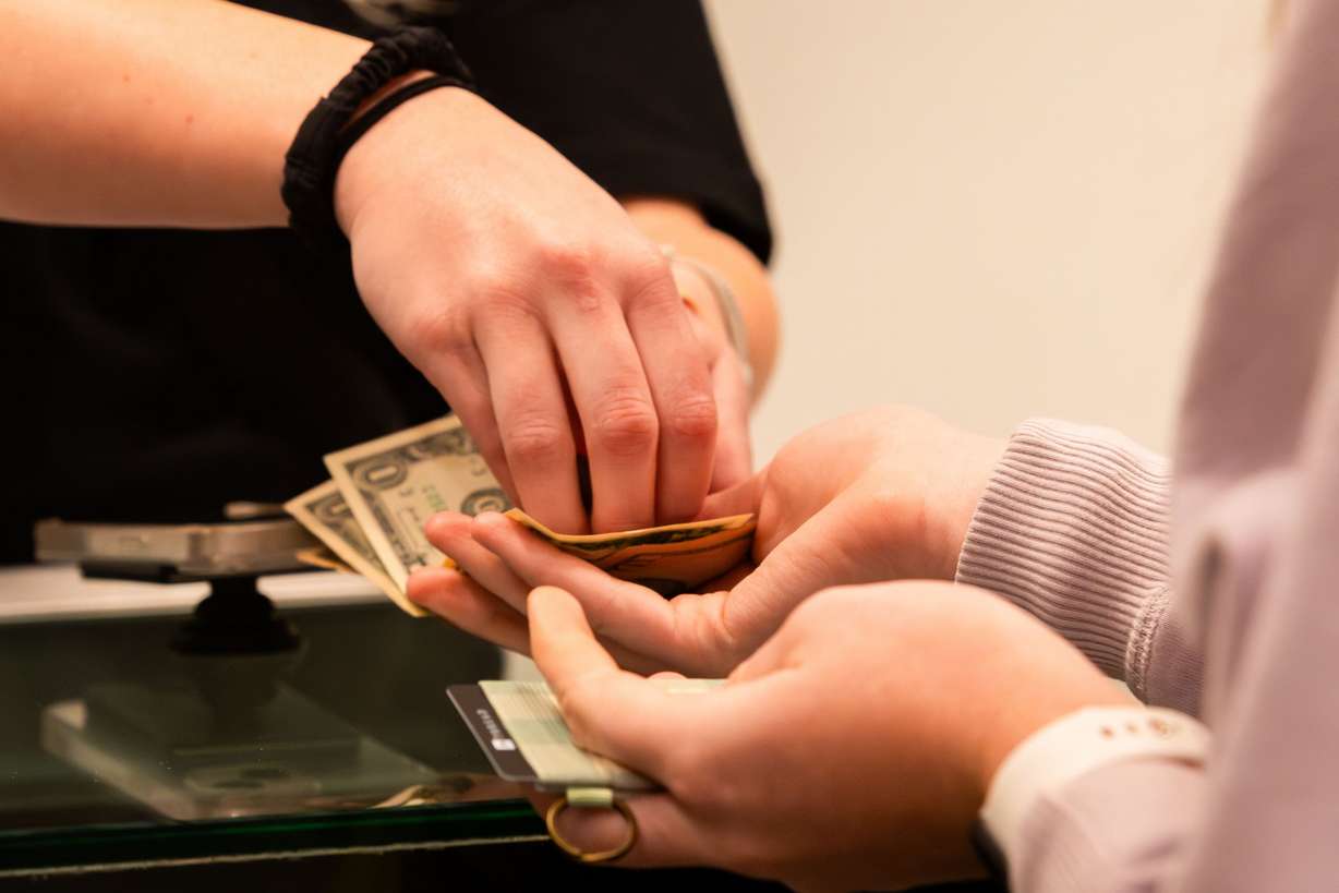 An employee gives change to a customer at Thread at City Creek Center in Salt Lake City on Friday, Nov. 24, 2023.