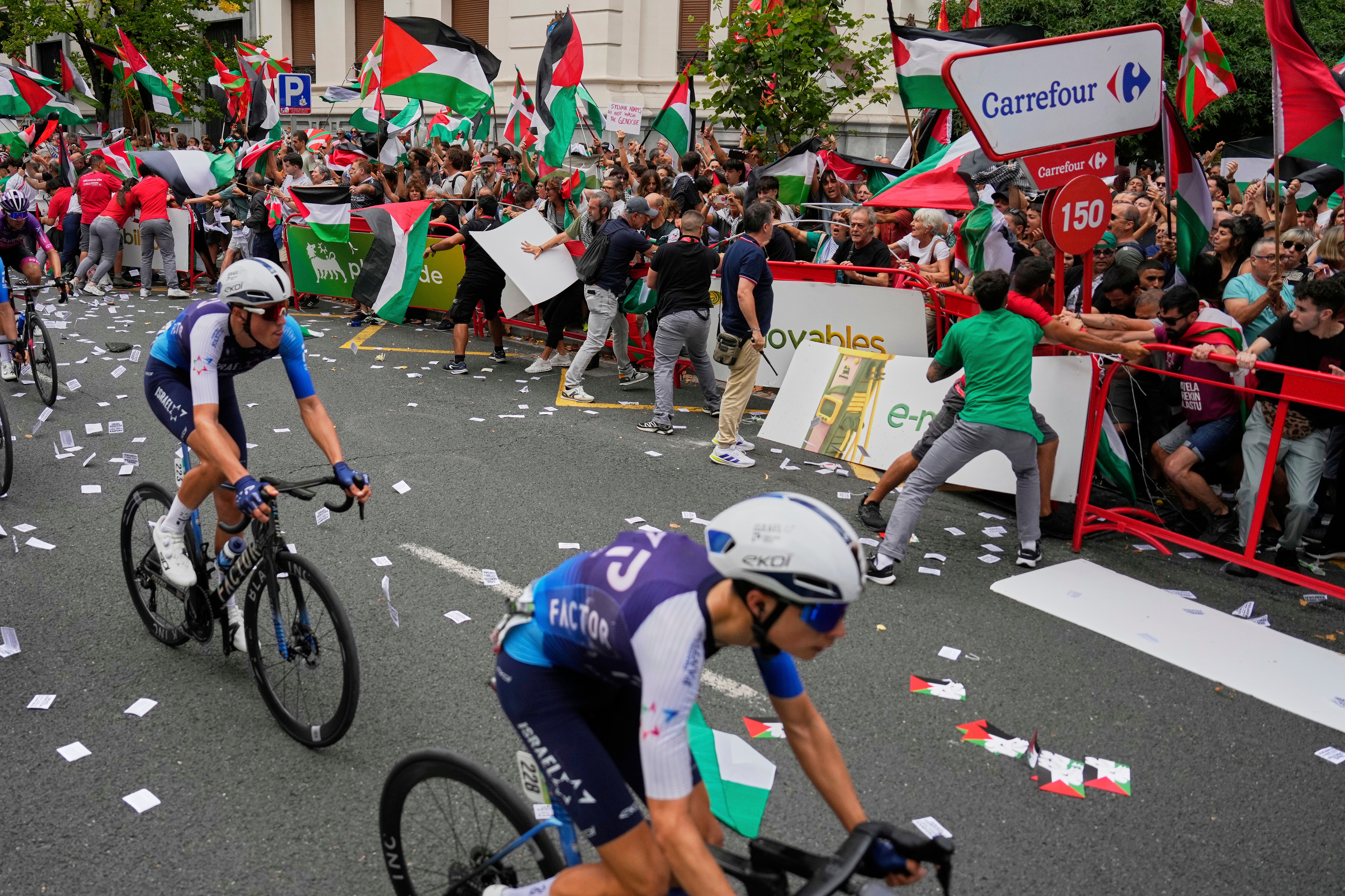 FILE - Riders of the Israel Premier Tech team compete as people holding Palestinian flags try to disrupt the eleventh stage of the Spanish Vuelta cycling race, from Bilbao to Bilbao, Spain, Wednesday, Sept. 3, 2025.