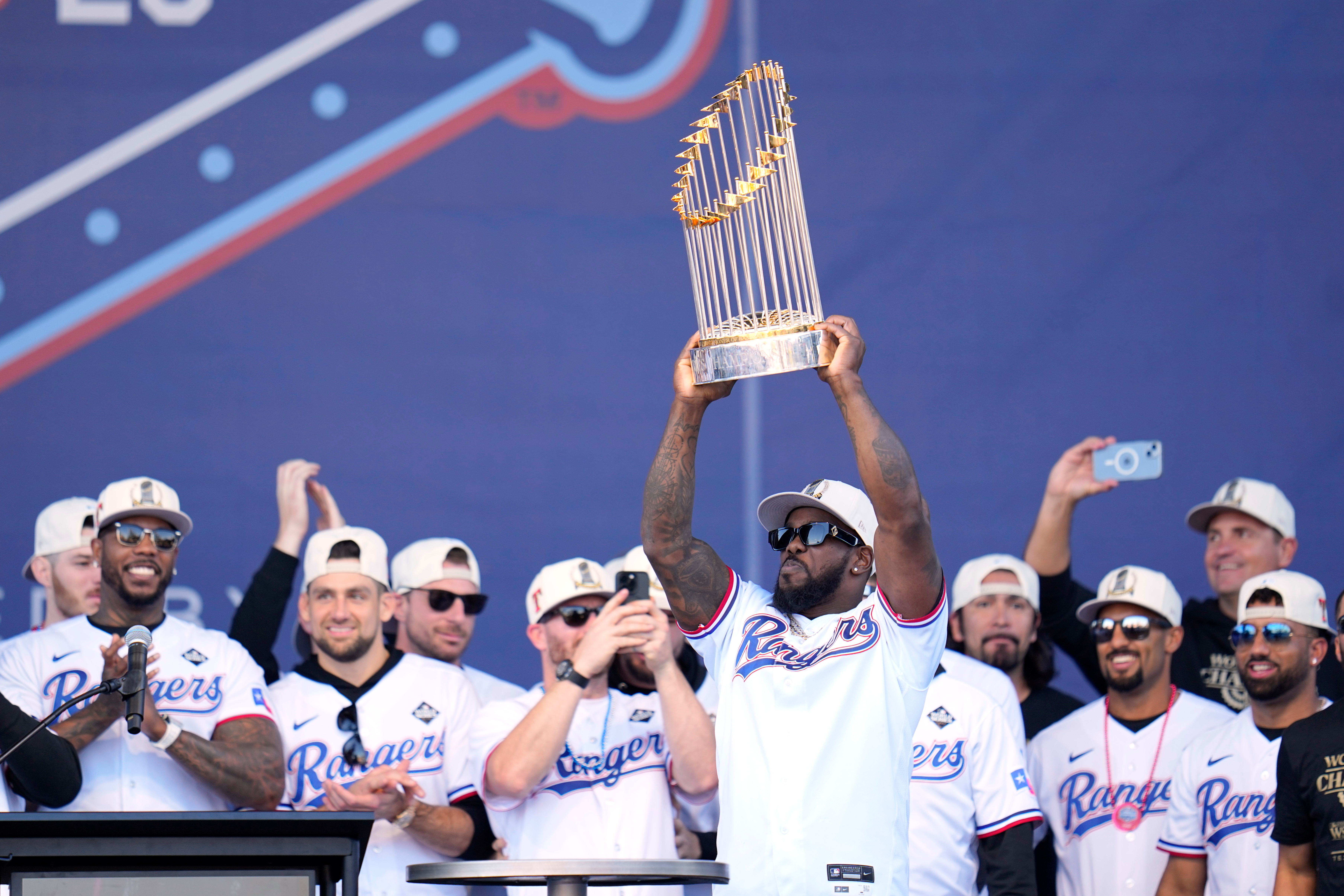 FILE - Texas Rangers' Adolis Garcia, surrounded by teammates and staff, holds up the Commissioner's Trophy during a World Series baseball championship celebration, Friday, Nov. 3, 2023, in Arlington, Texas.
