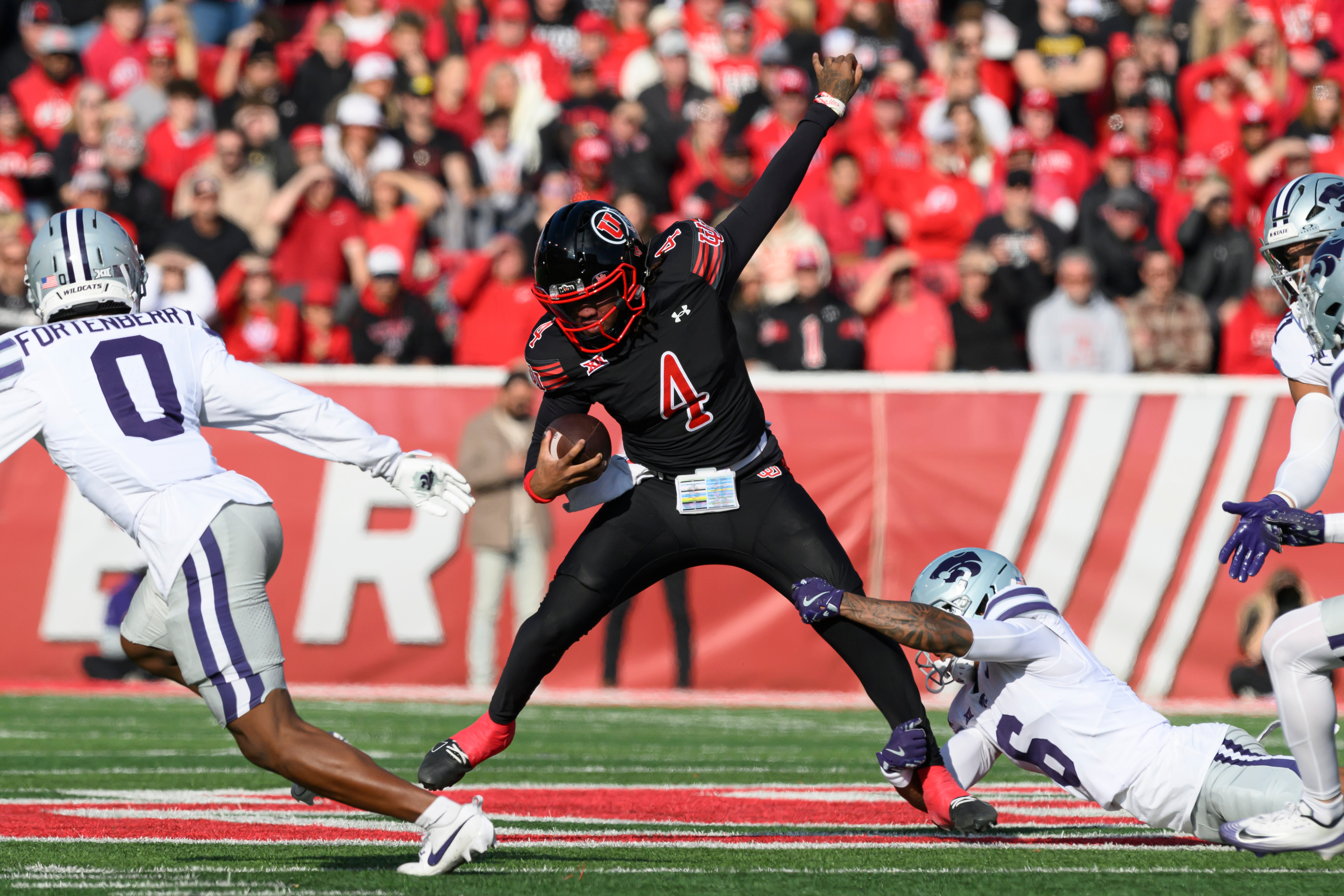 Utah quarterback Devon Dampier (4) is tackled by Kansas State defensive back Qua Moss, bottom right, during the first half of an NCAA college football game, Saturday, Nov. 22, 2025, in Salt Lake City. 