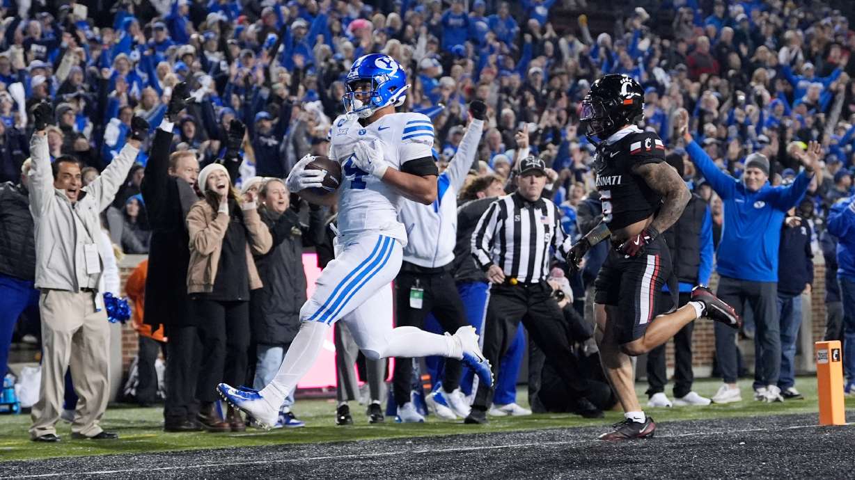 BYU running back LJ Martin (4) scores a touch down past Cincinnati safety Christian Harrison (5) during the second half of an NCAA college football game, Saturday, Nov. 22, 2025, in Cincinnati.