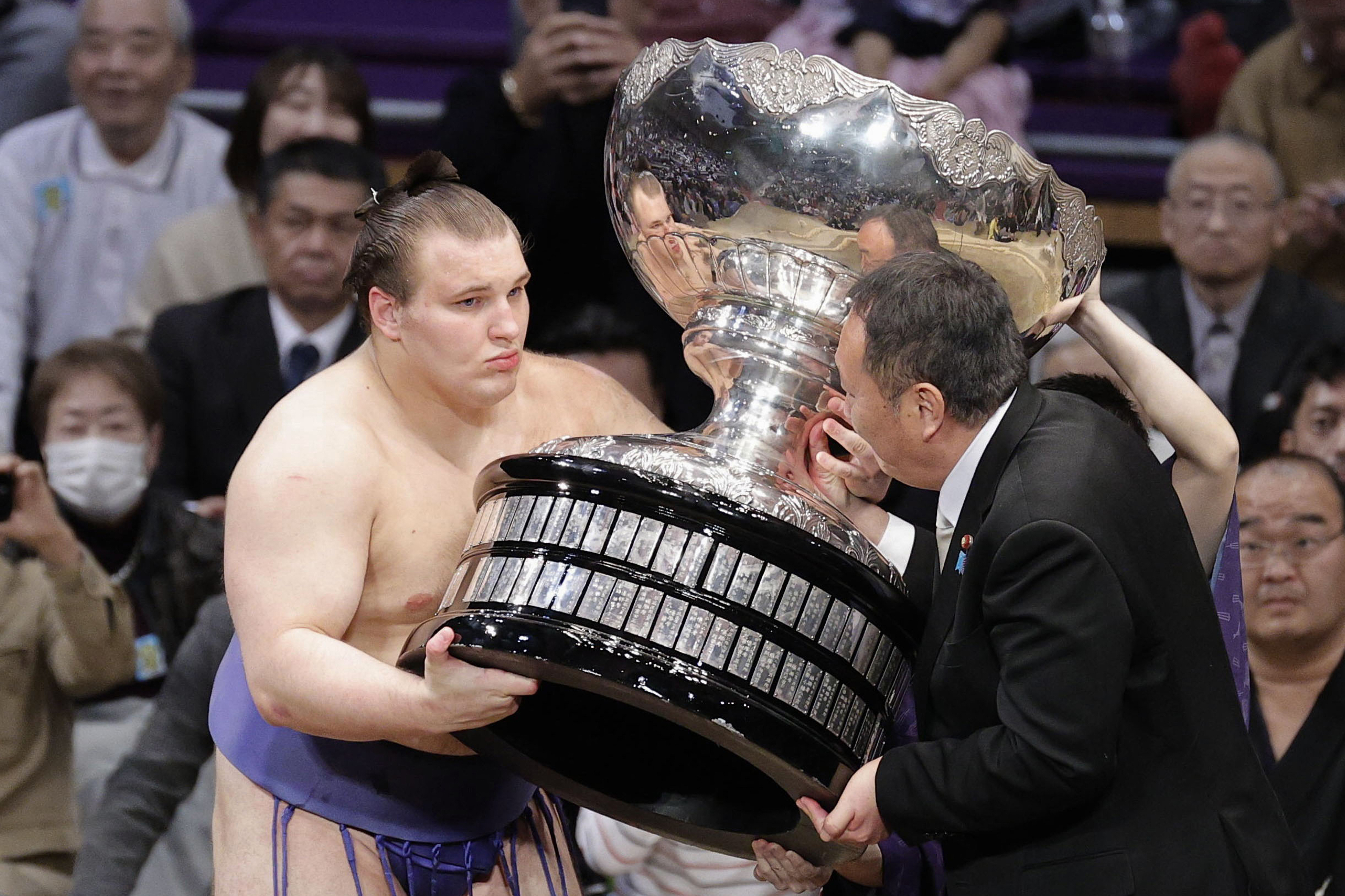 Ukrainian Aonishiki, left, receives a trophy after winning the Kyushu Grand Sumo Tournament in Fukuoka, western Japan, Sunday, Nov. 23, 2025. 