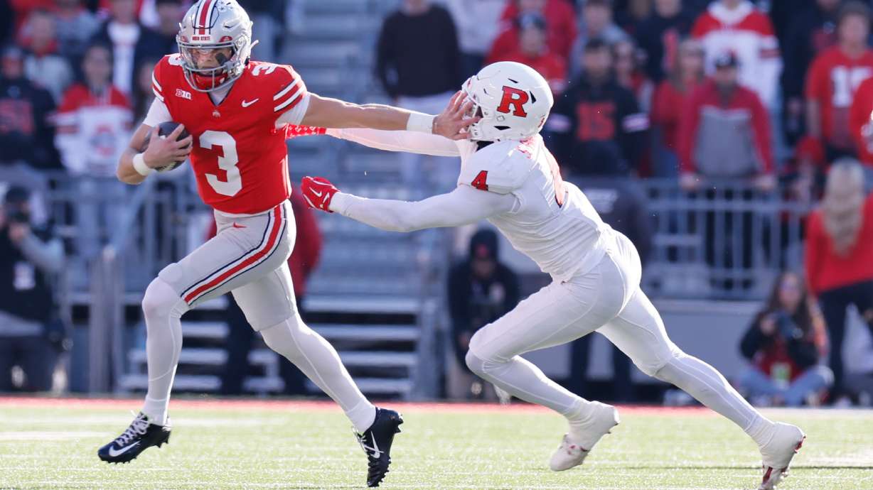 Ohio State quarterback Lincoln Kienholz, left, stiff arms Rutgers linebacker Sam Robinson during the second half of an NCAA college football game, Saturday, Nov. 22, 2025, in Columbus, Ohio.