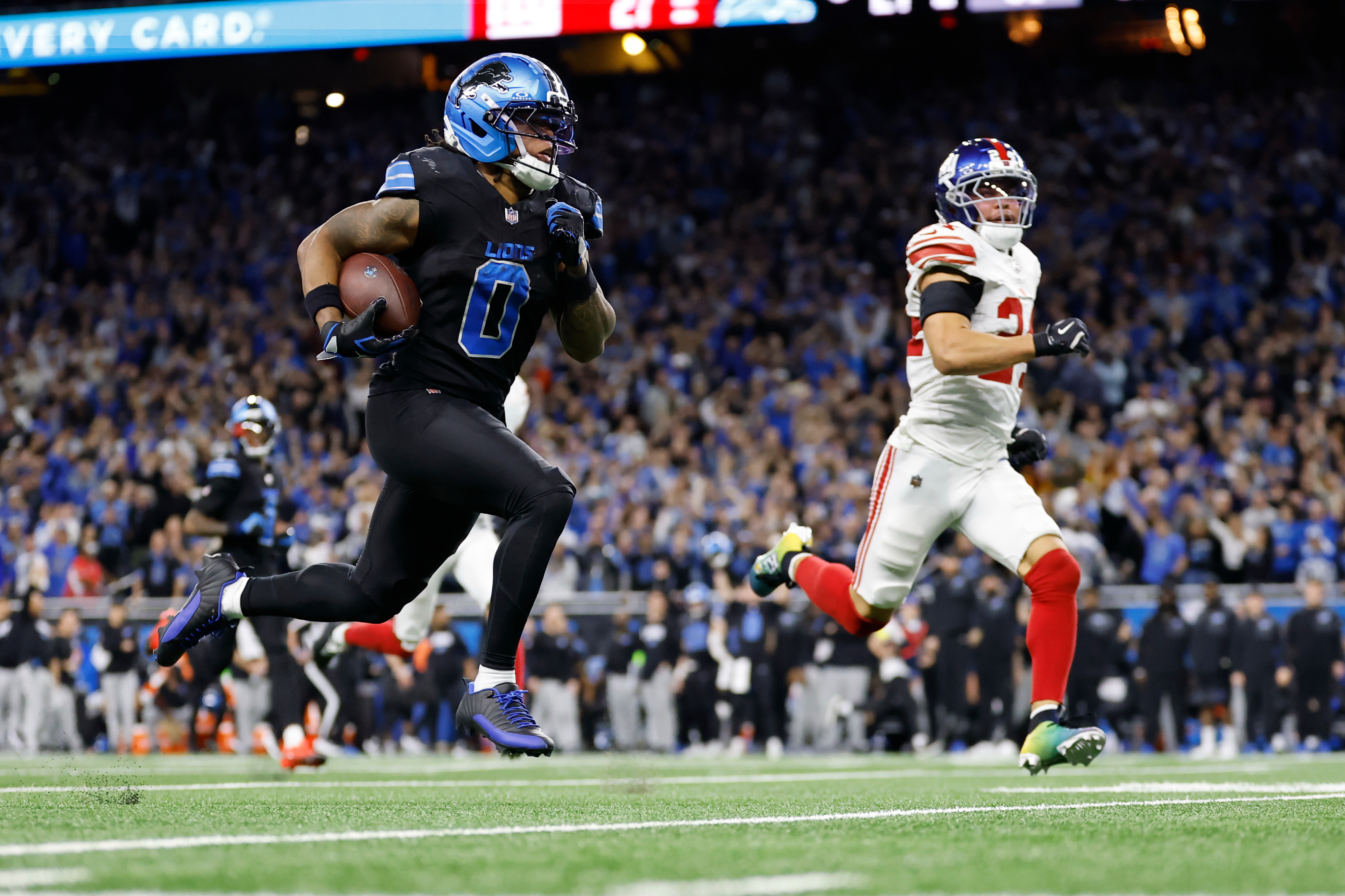 Detroit Lions running back Jahmyr Gibbs (0) runs past New York Giants safety Dane Belton (24) for a touchdown in overtime of an NFL football game in Detroit, Sunday, Nov. 23, 2025. 