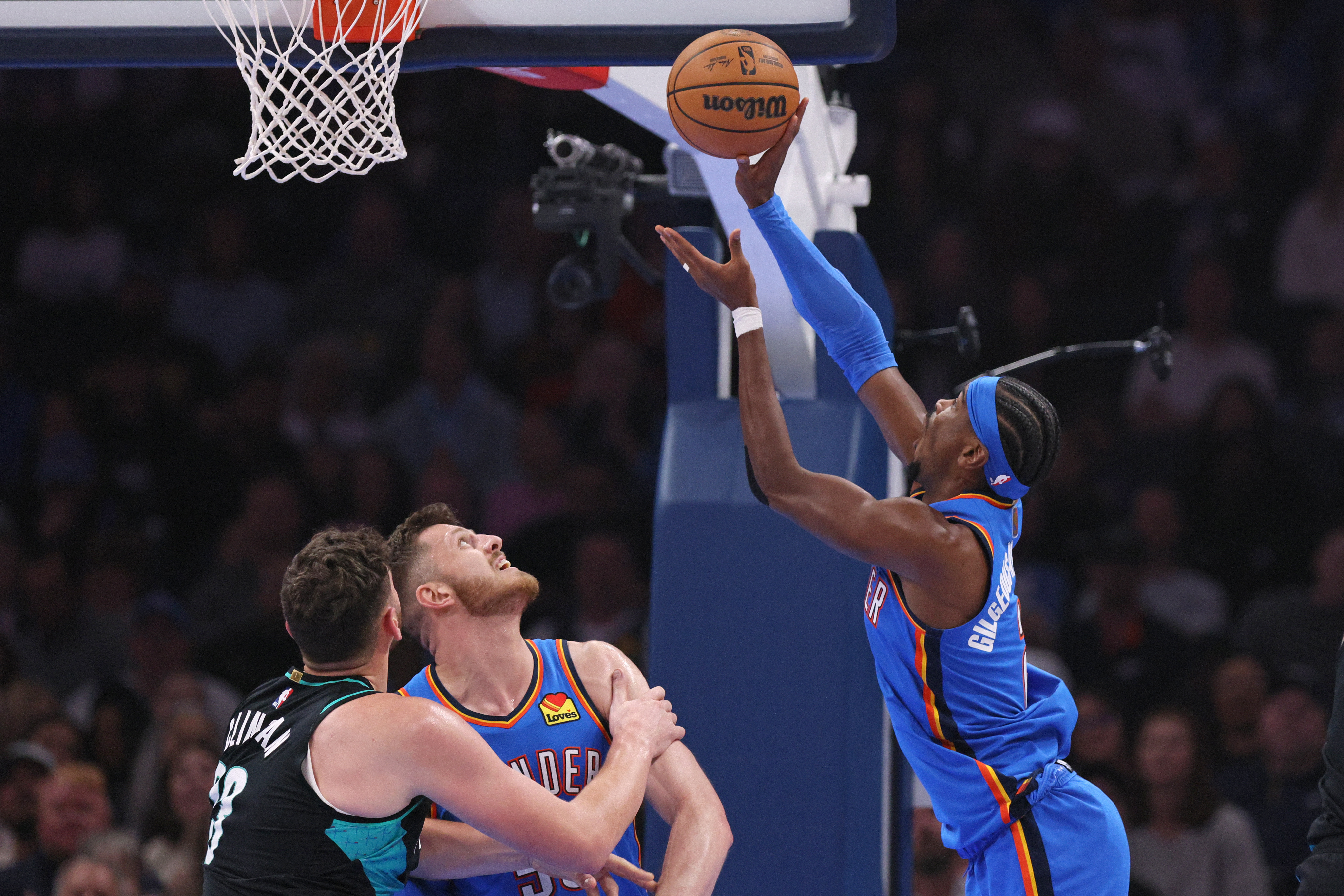 Oklahoma City Thunder guard Shai Gilgeous-Alexander, right, shoots next to Portland Trail Blazers center Donovan Clingan, left, and Thunder center Isaiah Hartenstein during the first half of an NBA basketball game, Sunday, Nov. 23, 2025, in Oklahoma City. 
