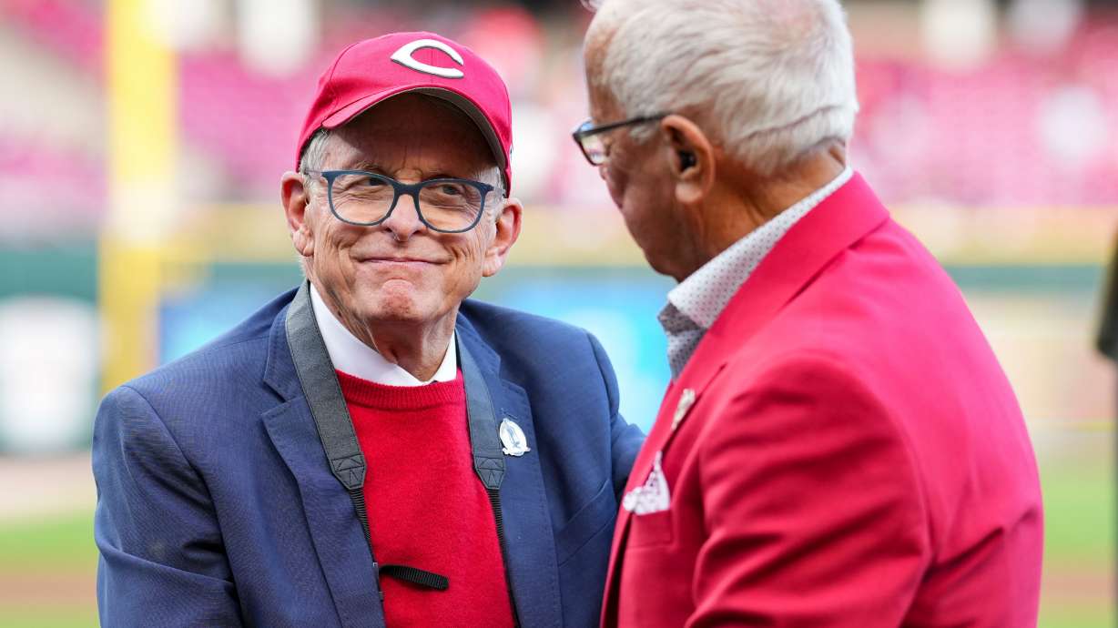 FILE - Hall of Fame broadcaster Marty Brennaman, right, speaks with Ohio Gov. Mike DeWine, left, during "Marty Brennaman Day" prior to a baseball game between the New York Mets and the Cincinnati Reds, Saturday, Sept. 6, 2025, in Cincinnati.