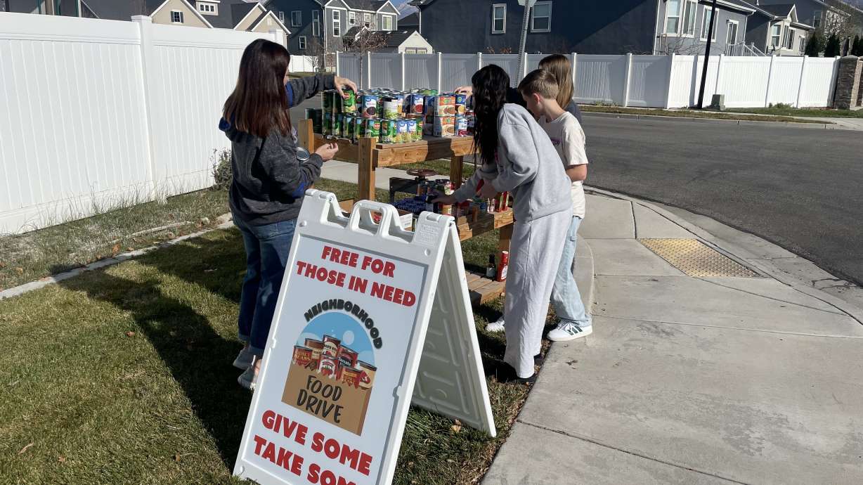 Paige Spaulding (left), along with her two daughters and a neighbor, fills a makeshift food bank in Lehi on Saturday.