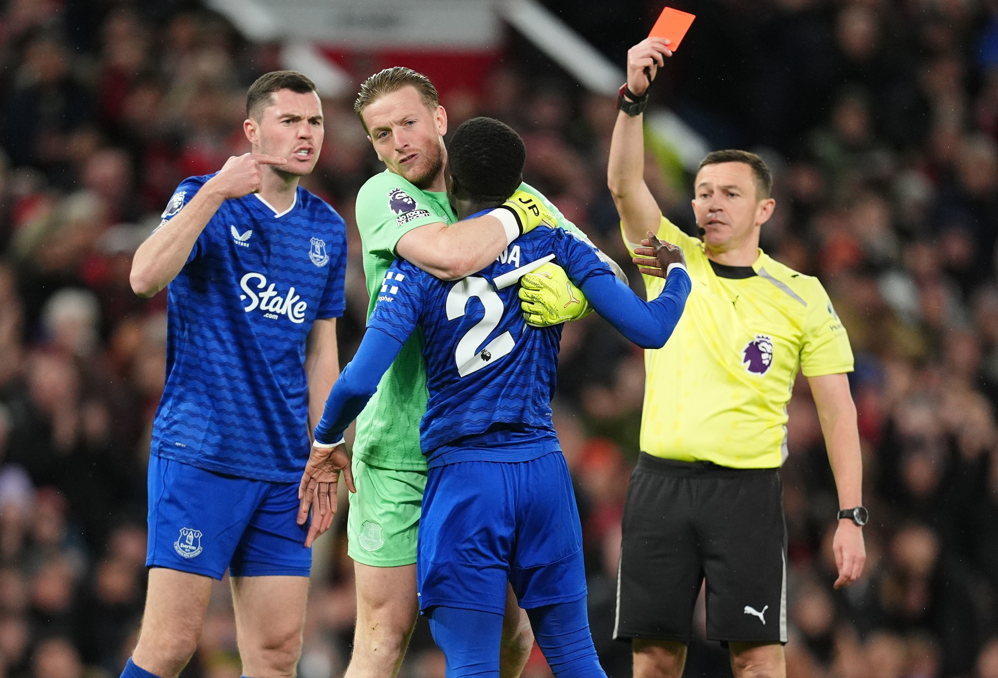 Everton's Idrissa Gueye, second right, is held back by teammate Jordan Pickford as he argues with Michael Keane, left, after getting a red card from referee Tony Harrington during the English Premier League soccer match between Manchester United and Everton in Manchester, England, Monday, Nov. 24, 2025. 