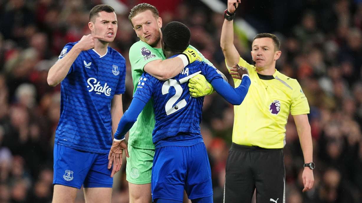 Everton's Idrissa Gueye, second right, is held back by teammate Jordan Pickford as he argues with Michael Keane, left, after getting a red card from referee Tony Harrington during the English Premier League soccer match between Manchester United and Everton in Manchester, England, Monday, Nov. 24, 2025.